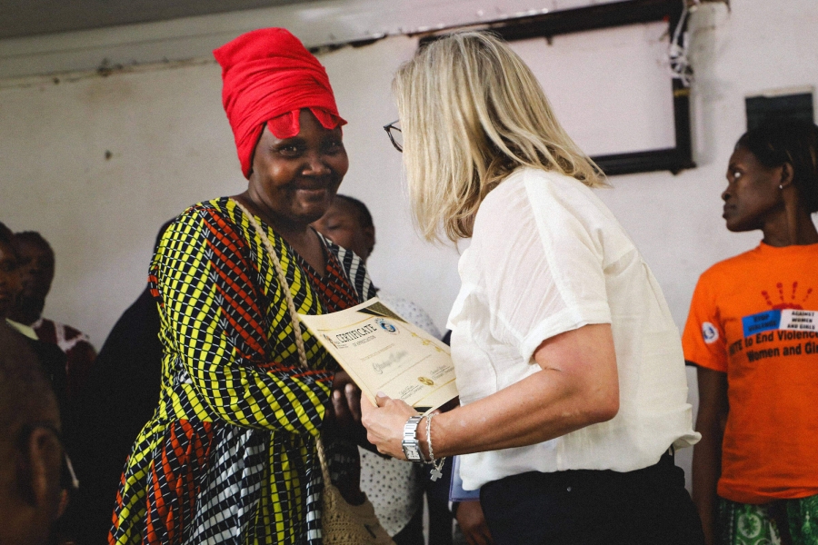 Two women shaking hands, one dressed in traditional Kenyan garb