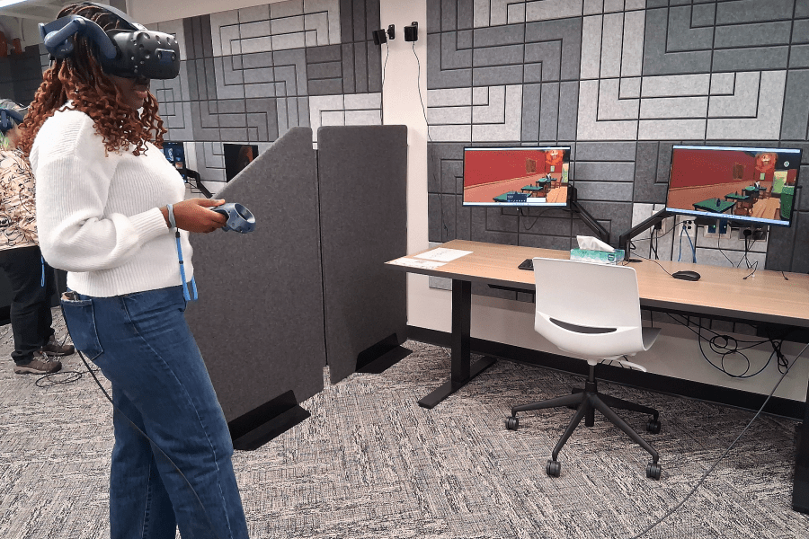 A woman using a VR headset in front of computers