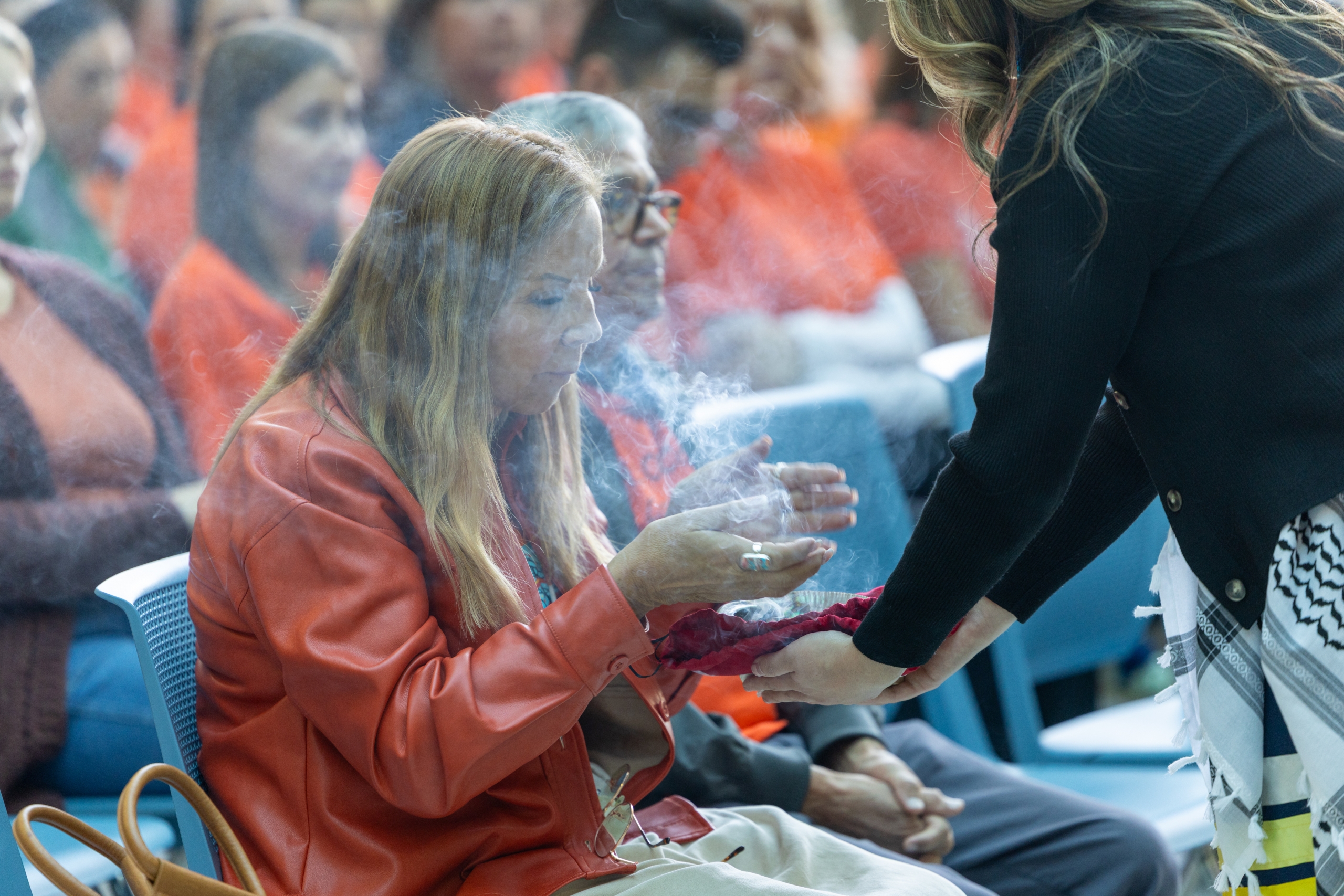 An event attendee fans sage during a smudging ceremony.