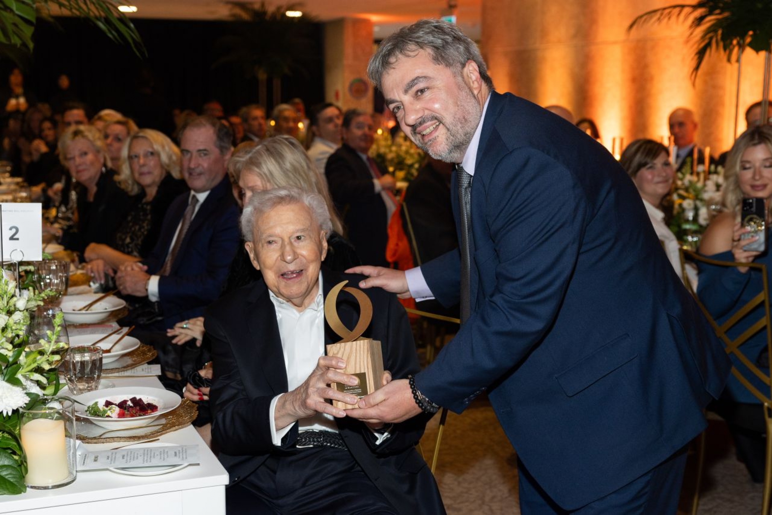 An elderly gentleman receiving an award from the school dean.