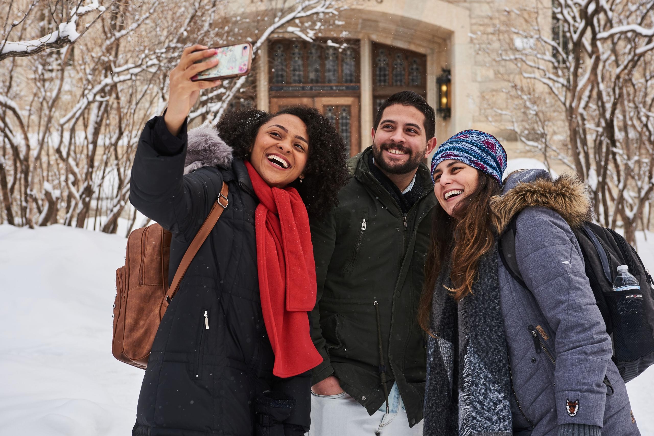 3 students take an outdoor selfie in the winter.