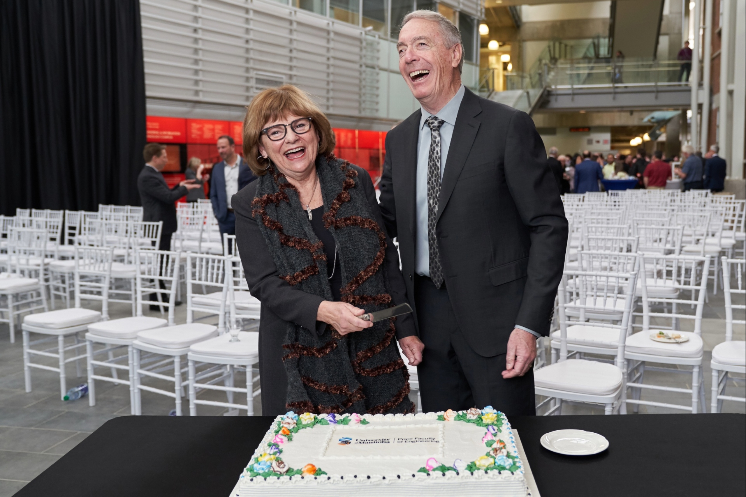 Gerry and Barb Price smiling as they're about to slice a large cake.