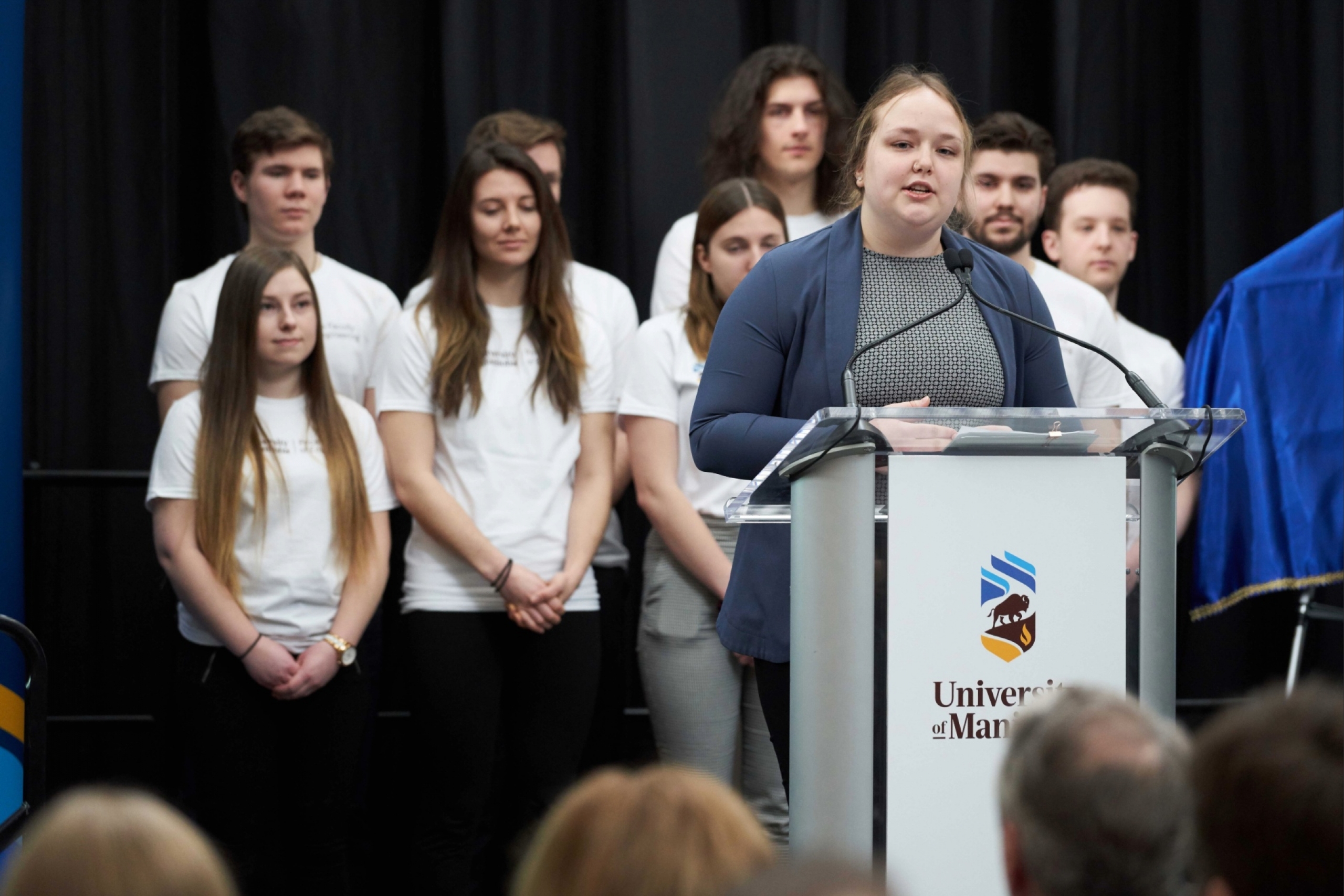 A speaker, the Senior Stick, speaks at a podium.