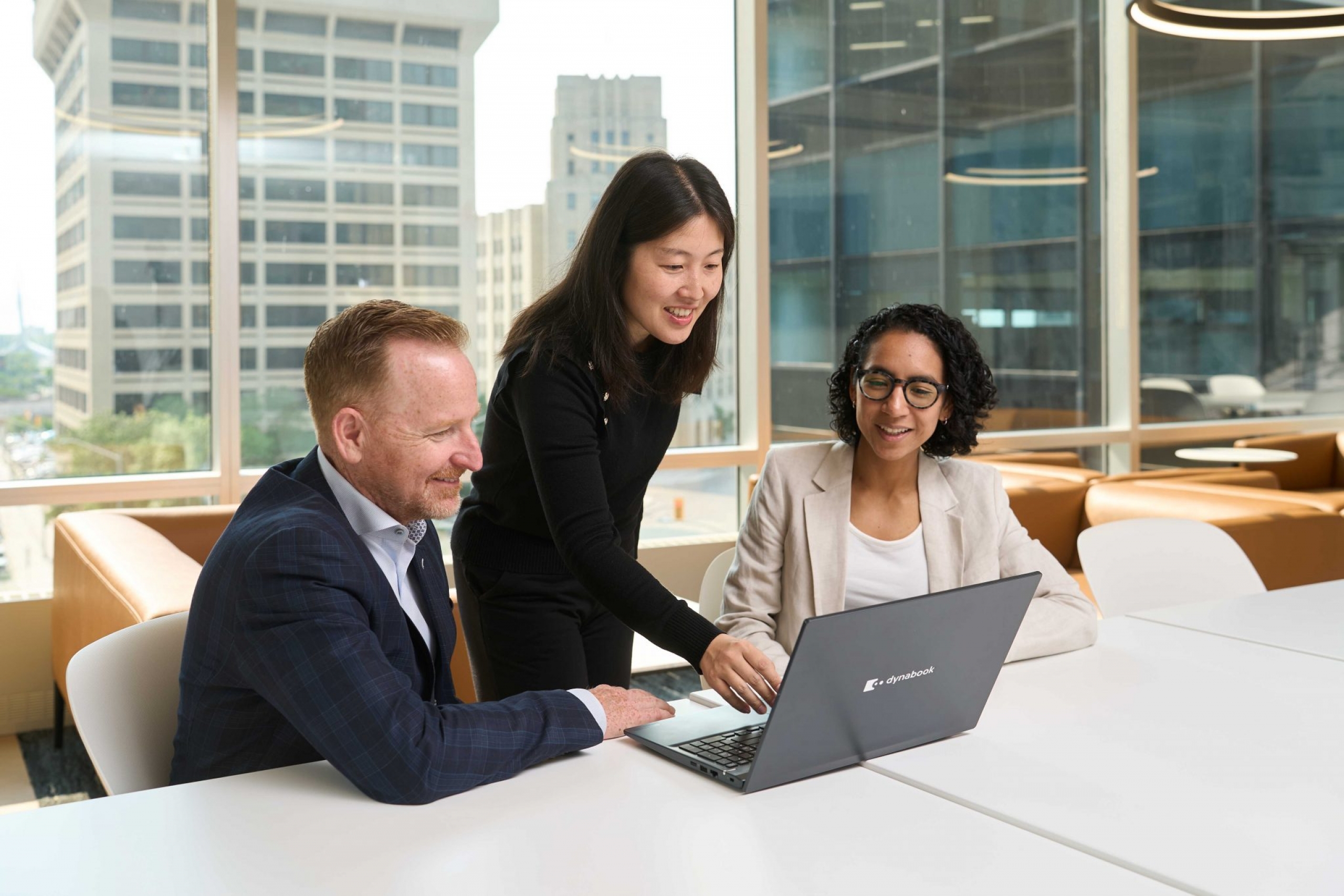 Three people in an office look at a computer