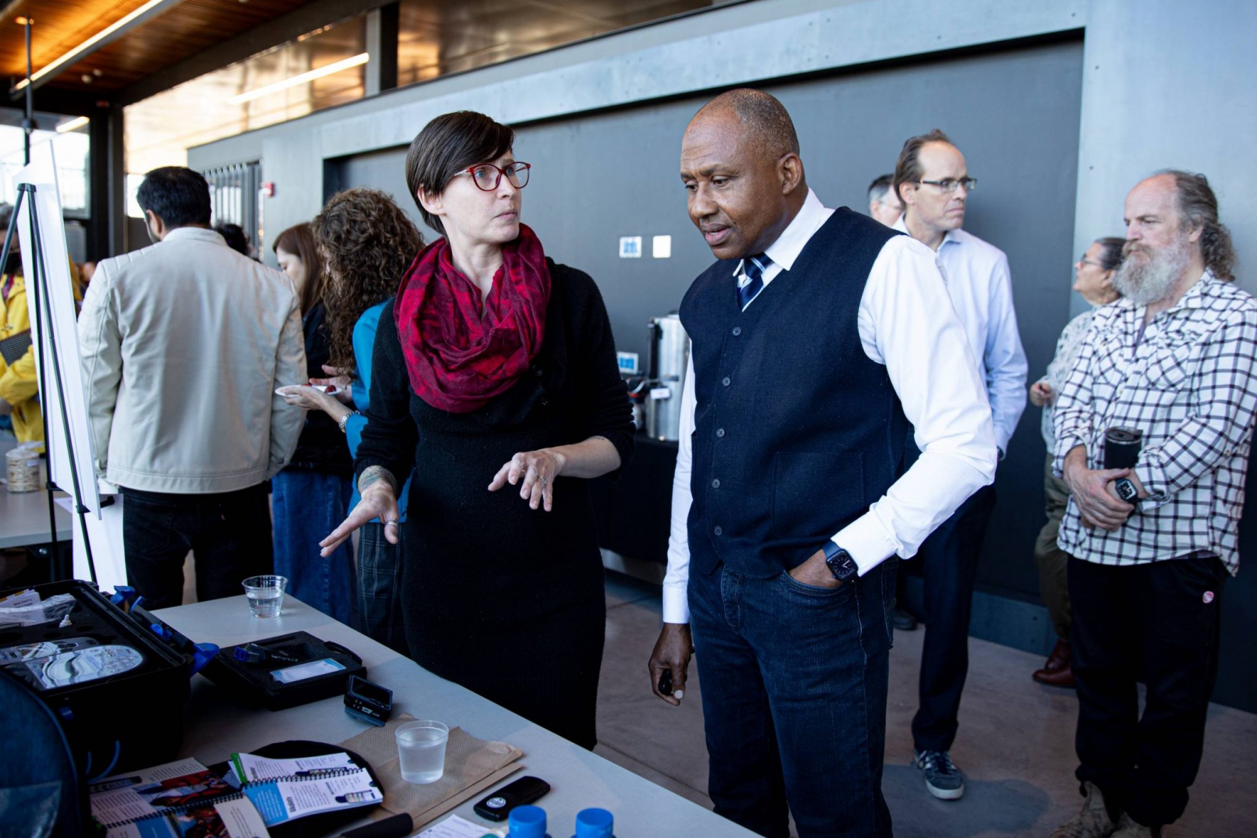 Two people stand in front of an information booth in conversation.