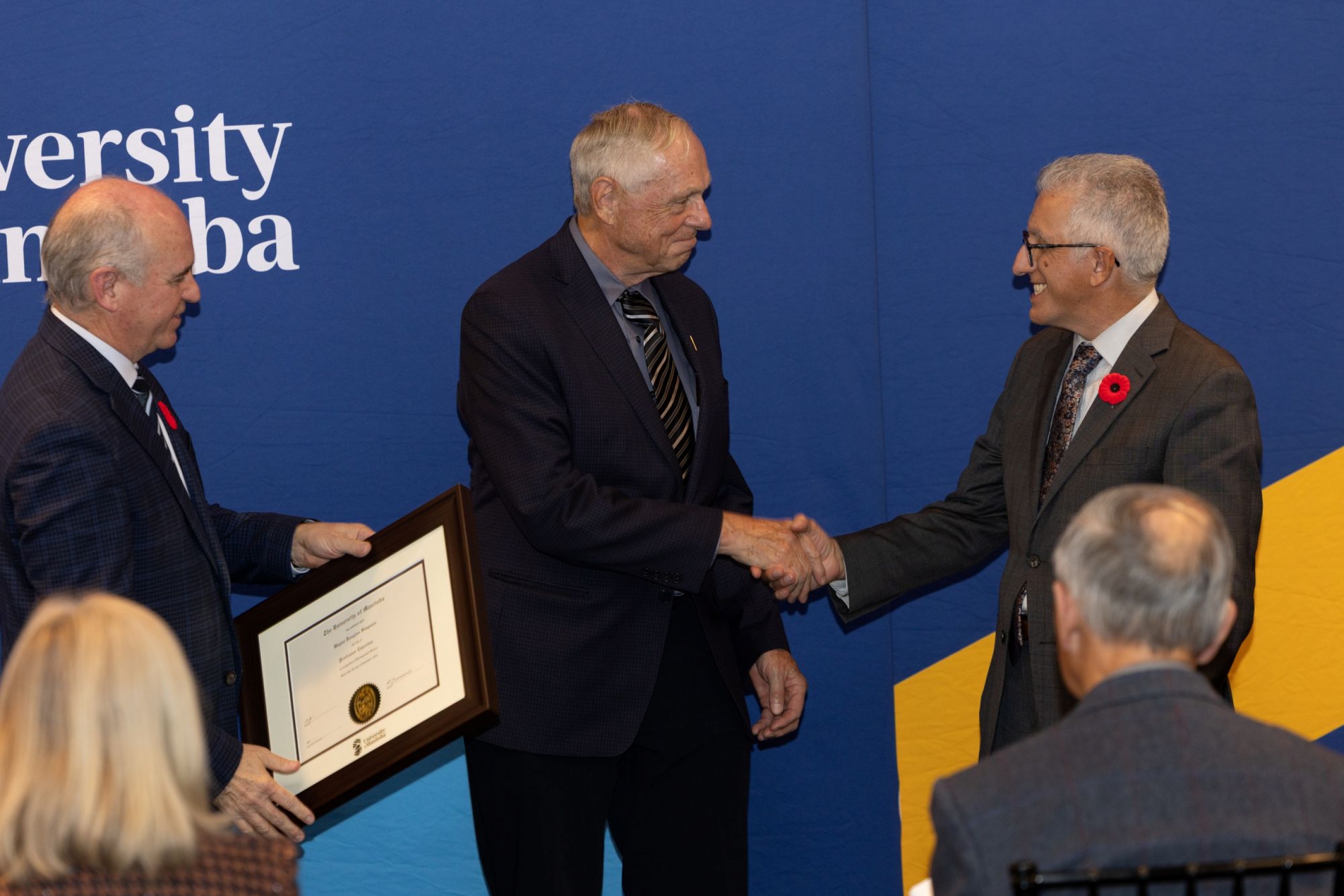 Chancellor Dave Angus and President Michael Benarroch present Wayne Simpson with certificate.