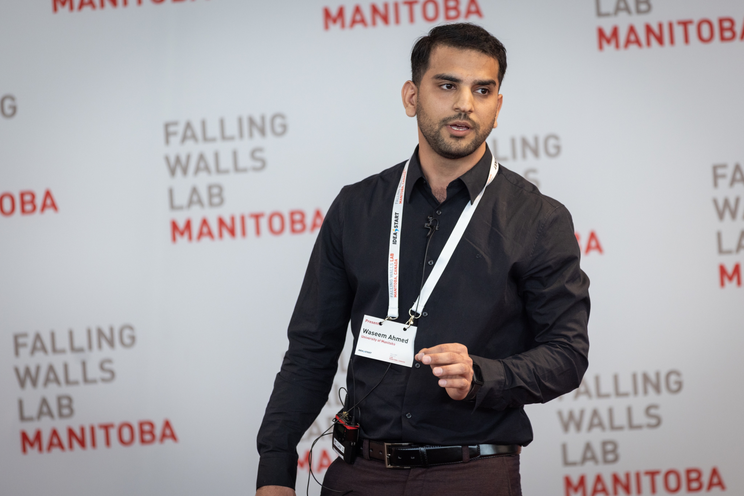 Waseem Ahmed presents on stage at Falling Walls Lab Manitoba 2026 in front of a branded event backdrop.