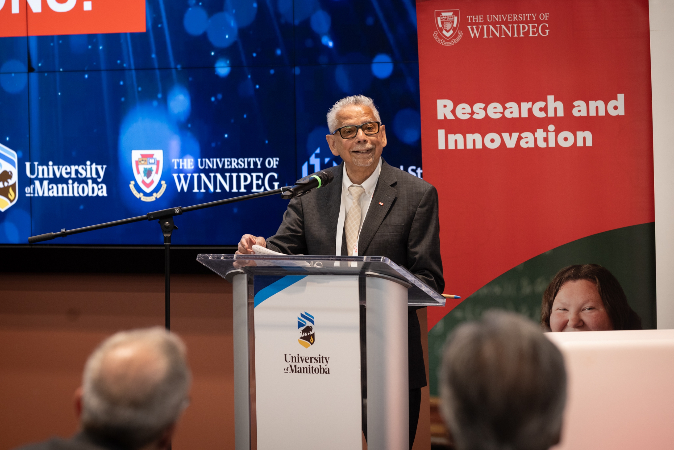 Dr. Mario Pinto speaks at a podium during Falling Walls Lab Manitoba 2026.