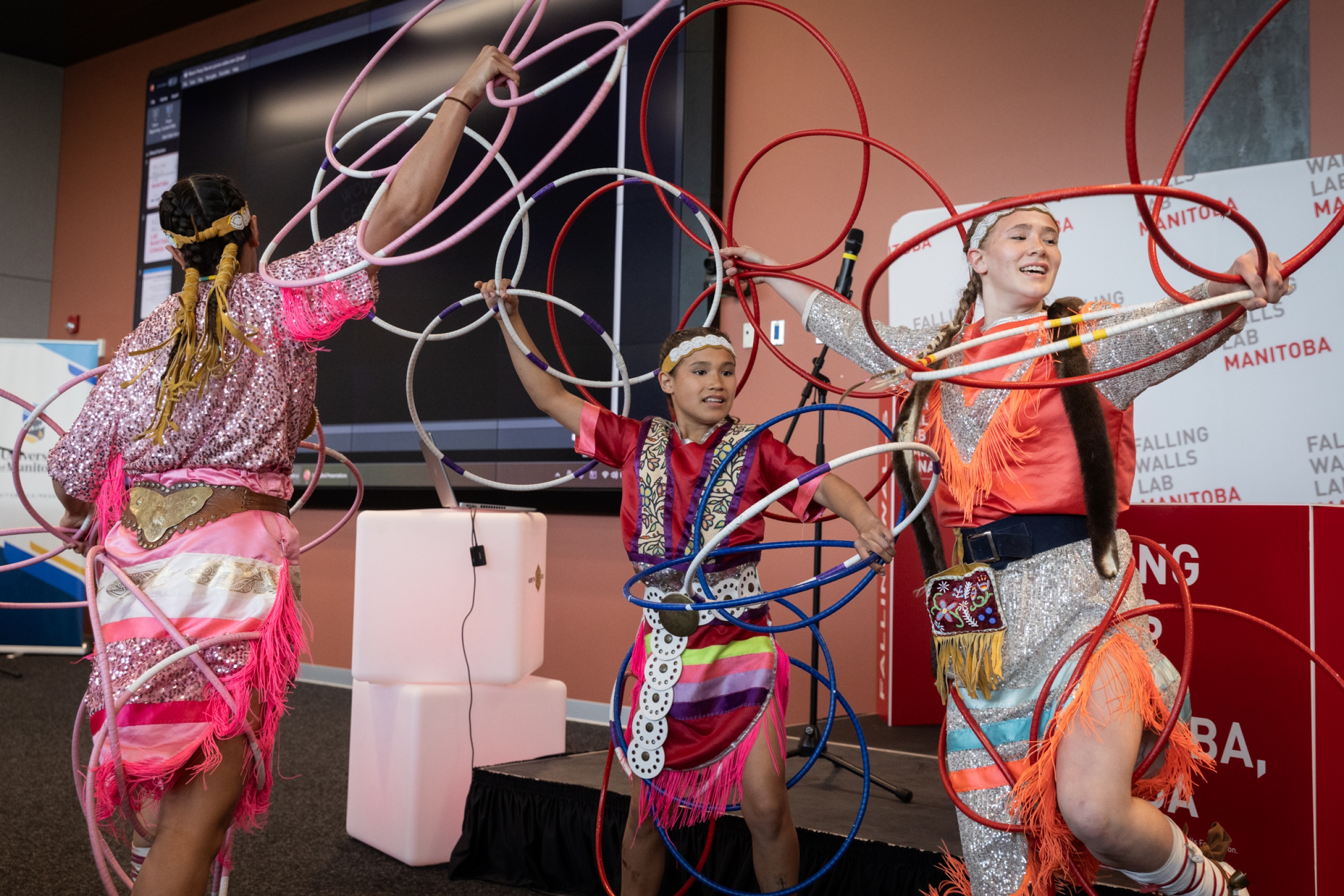 Three Mason Hoop Dancers perform with colourful hoops at Falling Walls Lab Manitoba 2026.