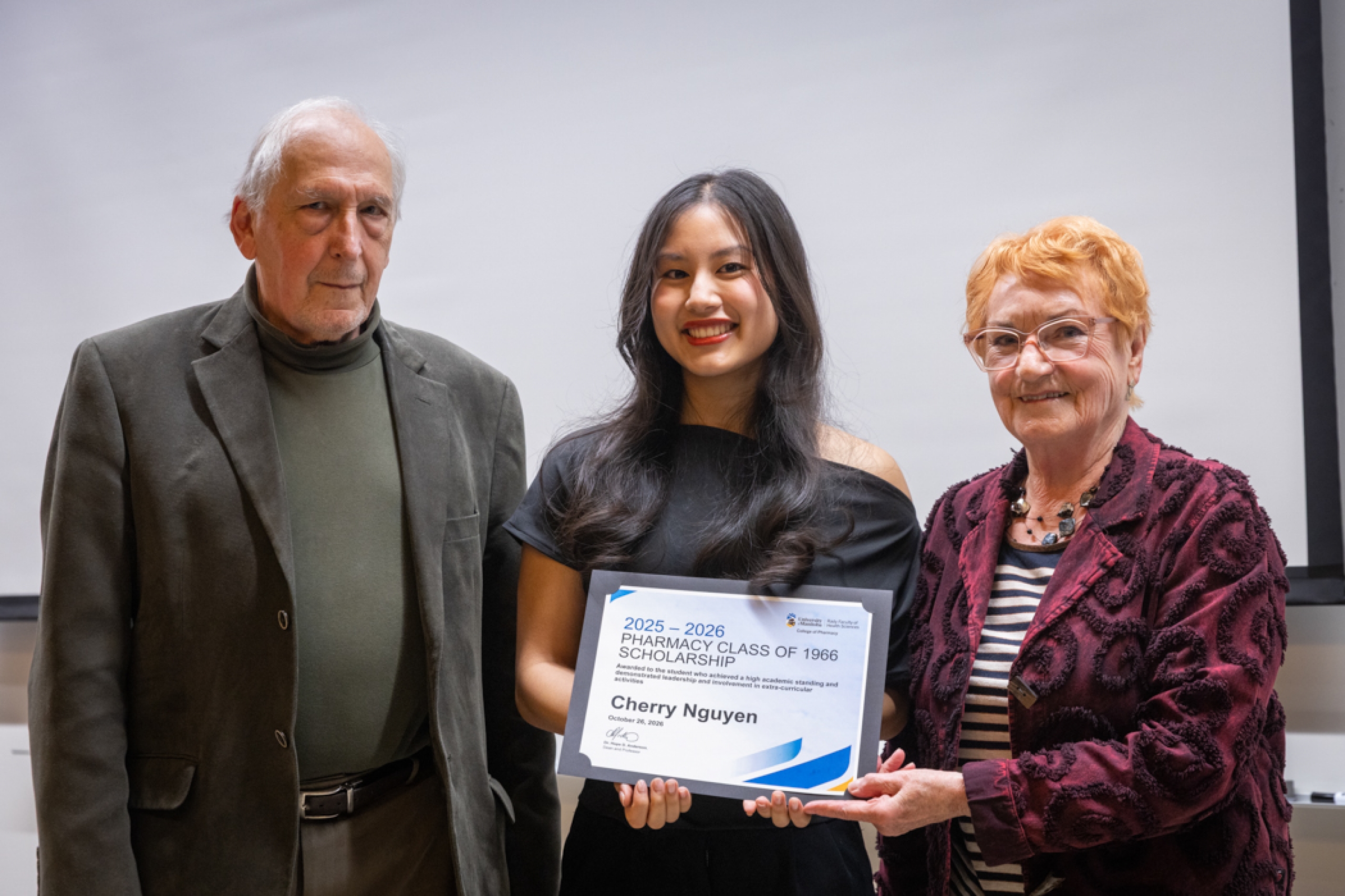 Two presenters giving recipient an award.