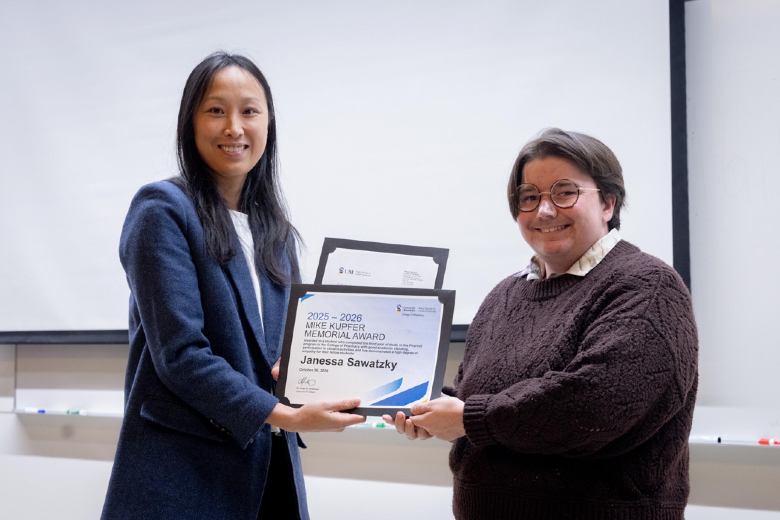 Pharmacy instructor handing student award.