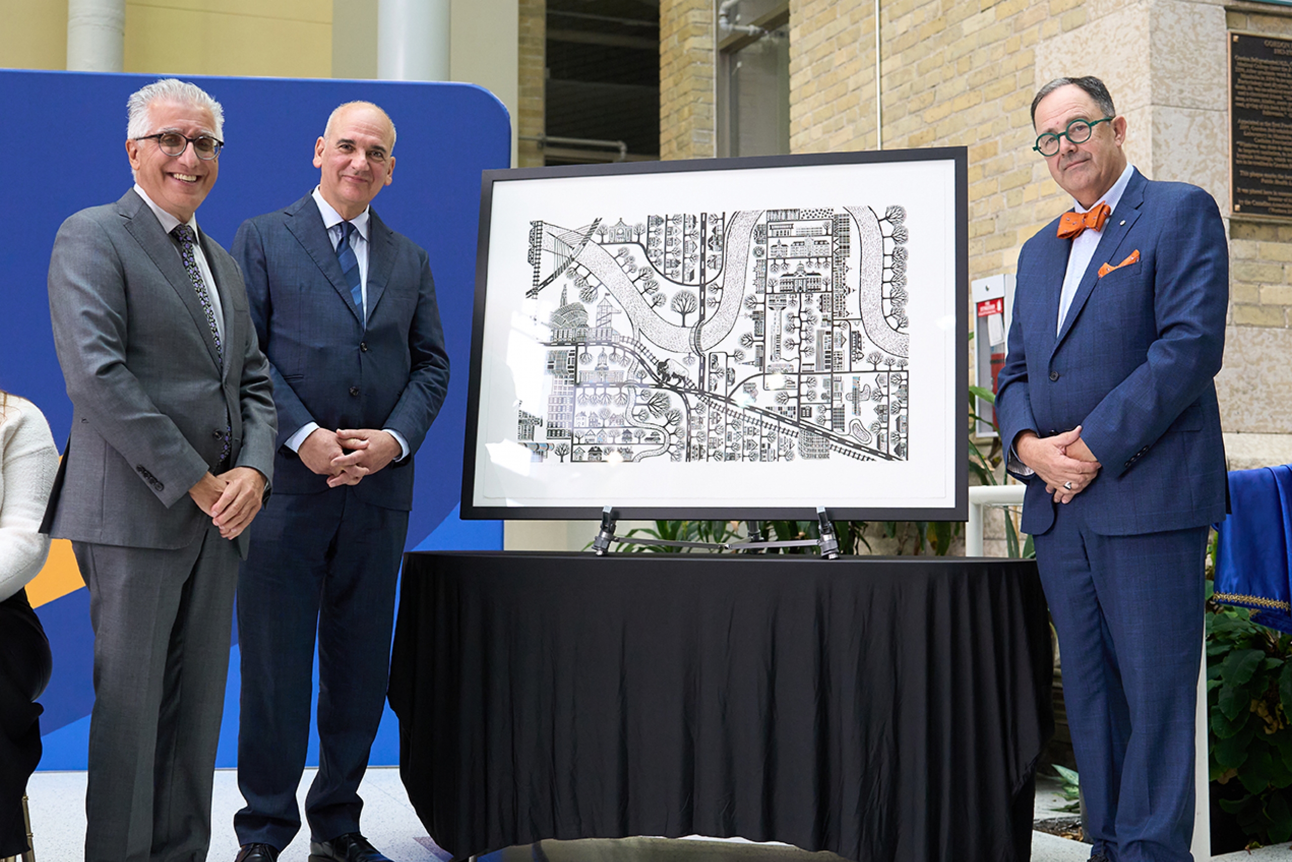 President Benarroch, Dr. Cholakis and Dr. Nickerson pose with a framed print