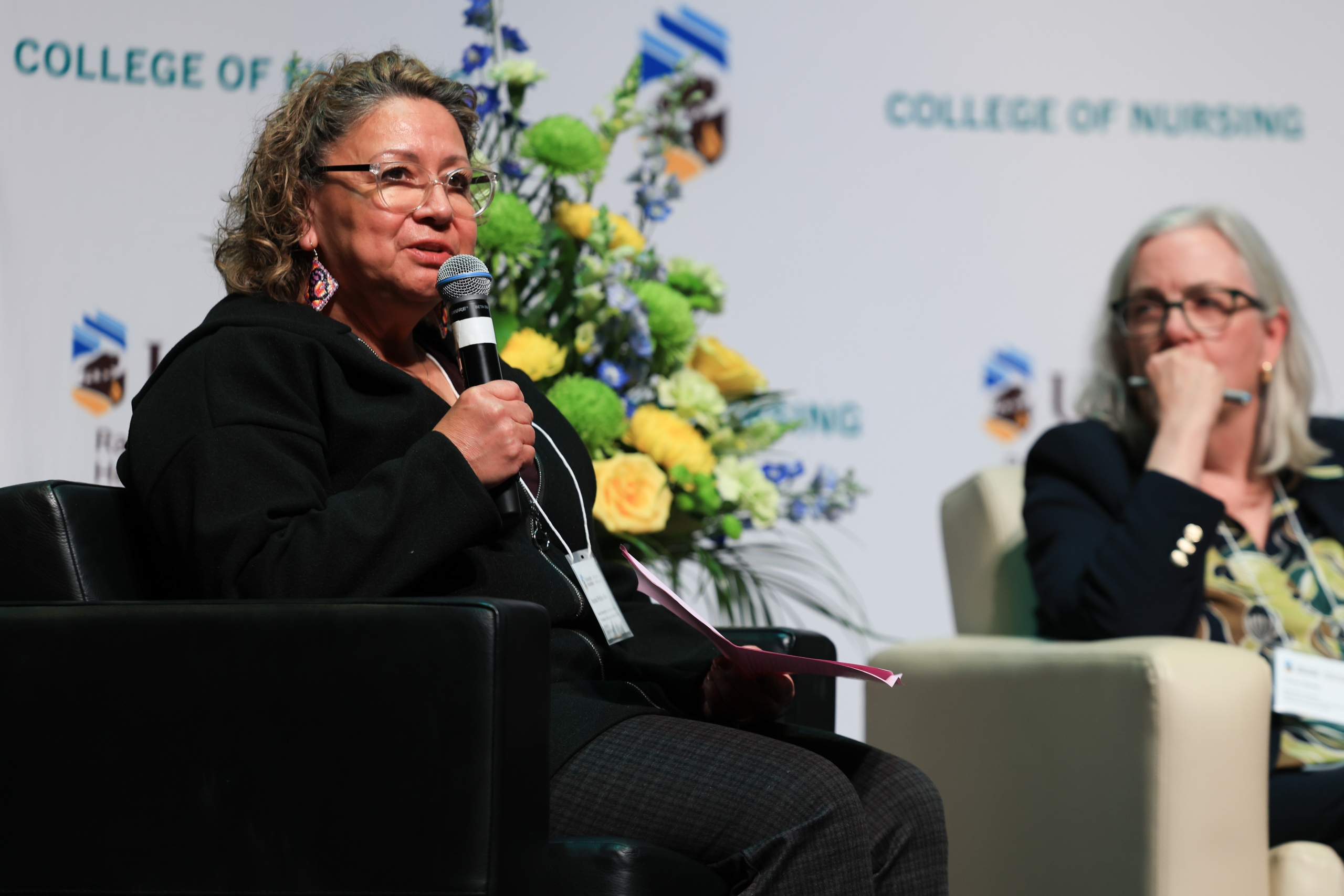 Dr. Wanda Phillips-Beck sits in a chair and speaks into a microphone.