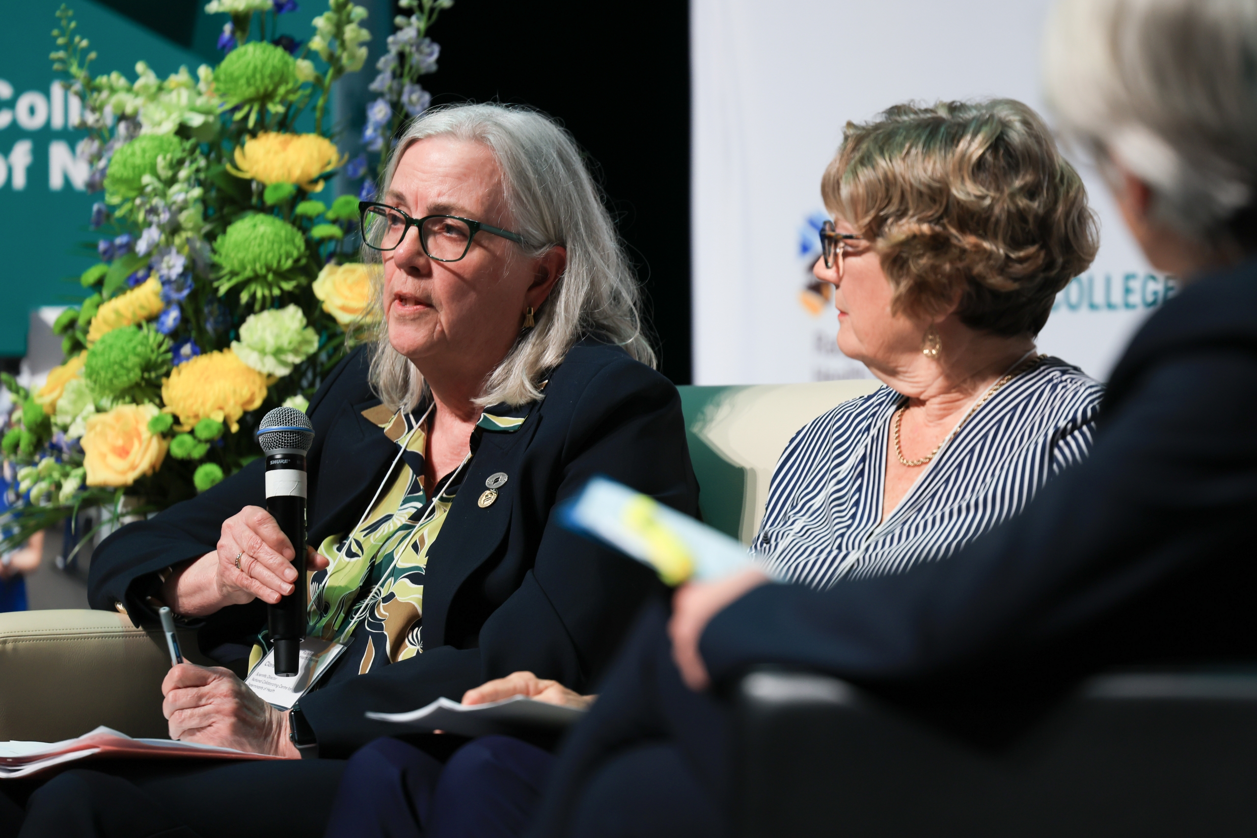 Dr. Claire Betker sits in a chair and speaks into a microphone.