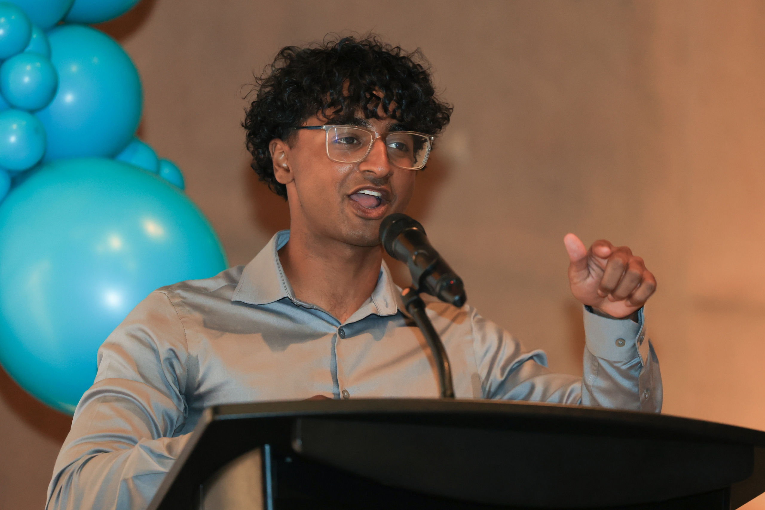 Bazil Hasan speaks at a podium.