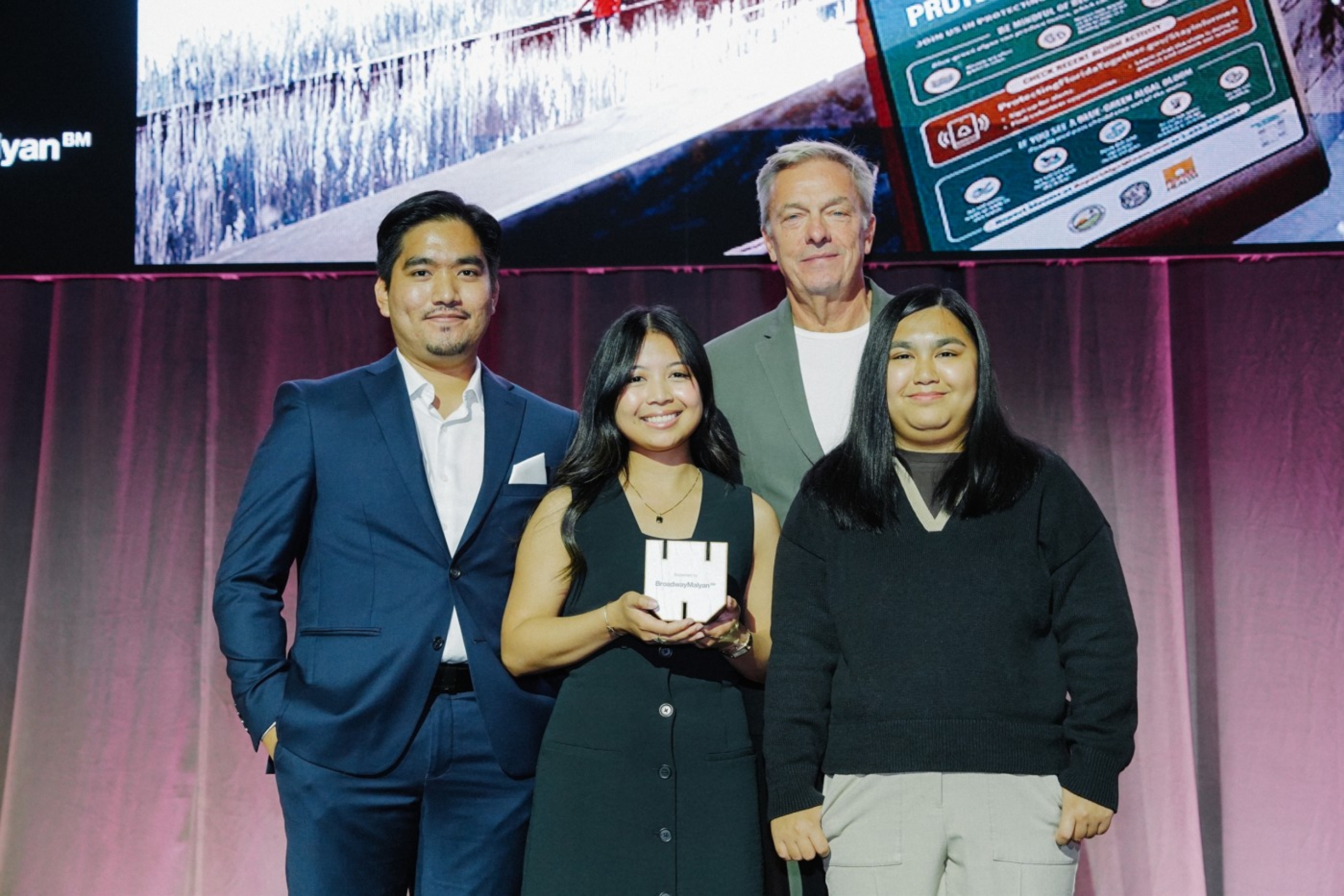 Four people pose on stage with an award.