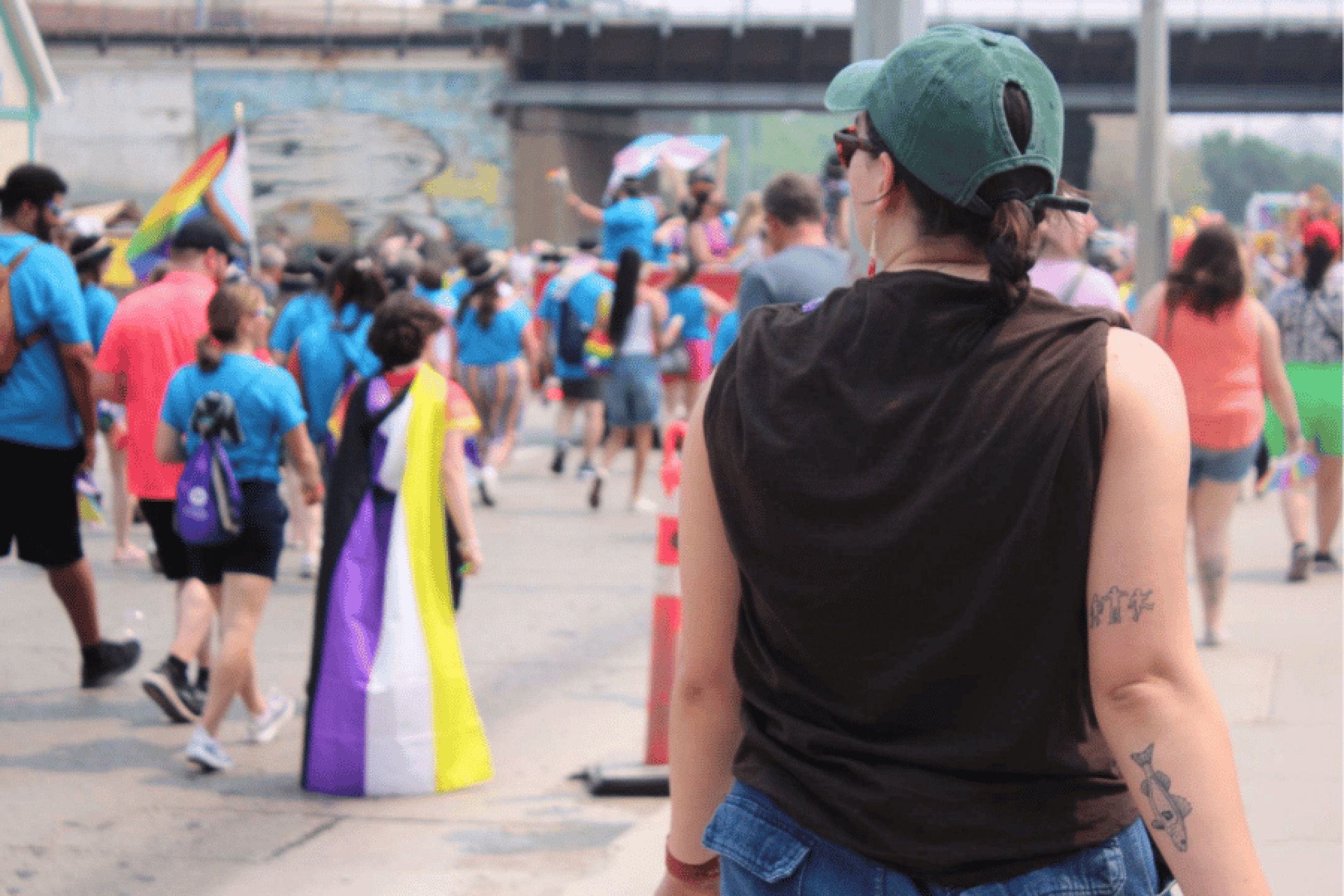 Community members walk together in a Pride parade carrying rainbow and Two-Spirit flags.