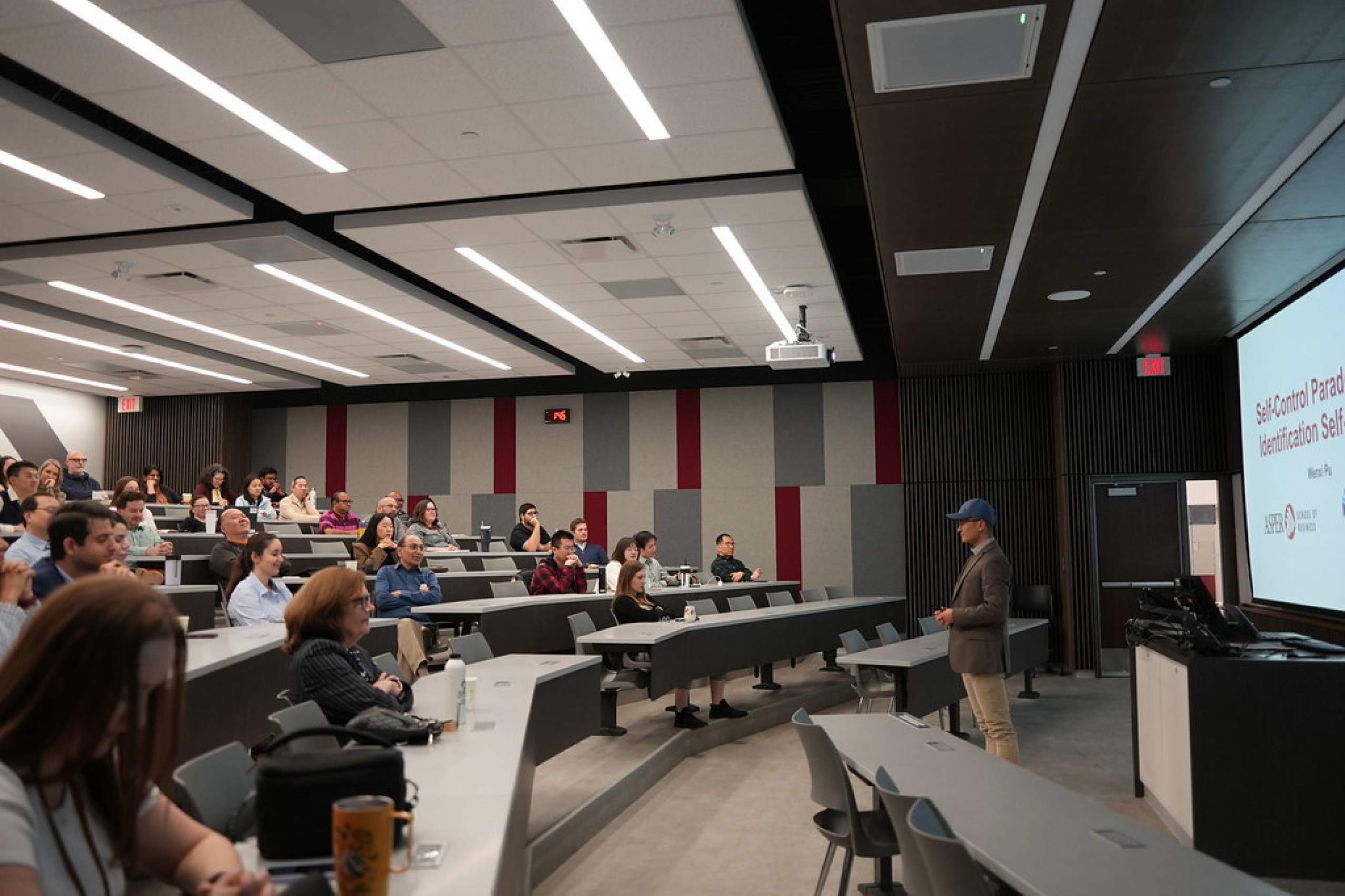 A professor gives a lecture at the front of a classroom