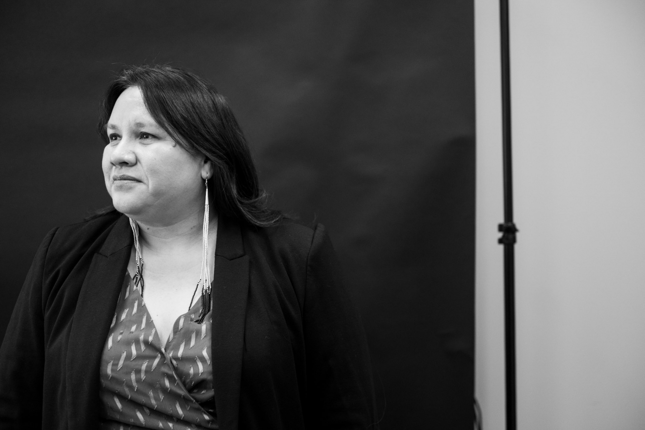 Black and white photo of Kathleen standing in front of a back drop. Side profile of Kathleen.