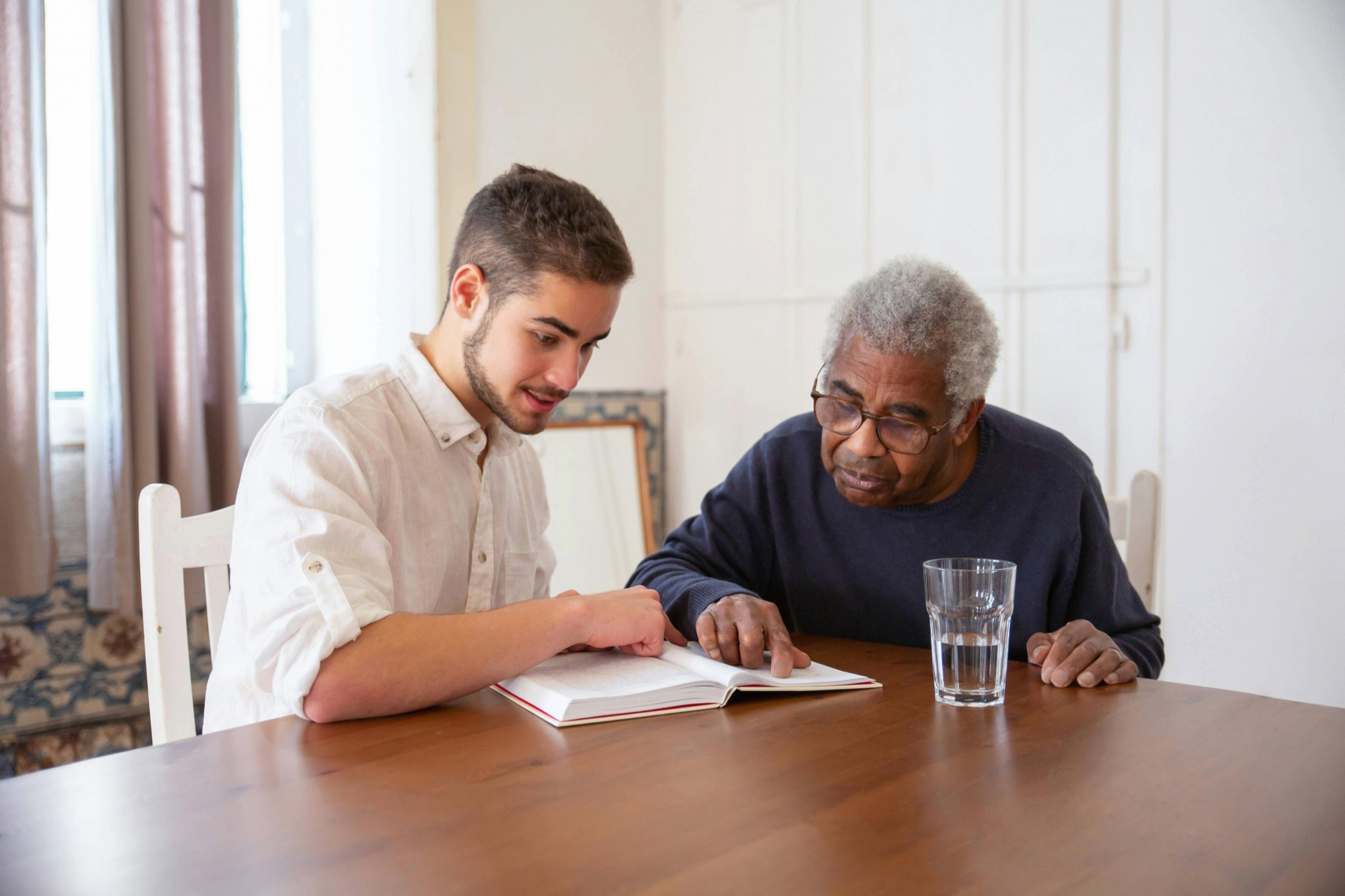 a young adult and older adult read together at a table