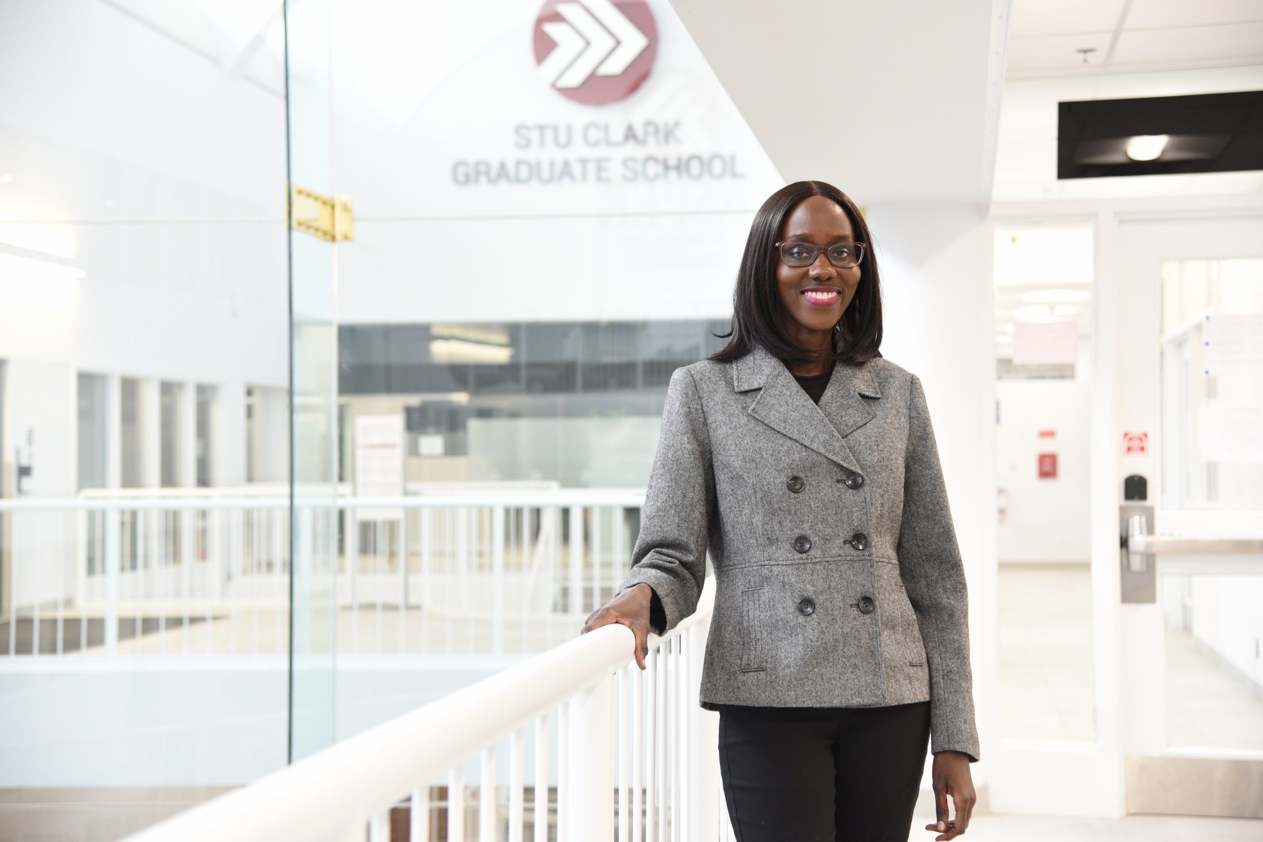 Angela Okware stands in front of a Stu Clark Graduate School sign
