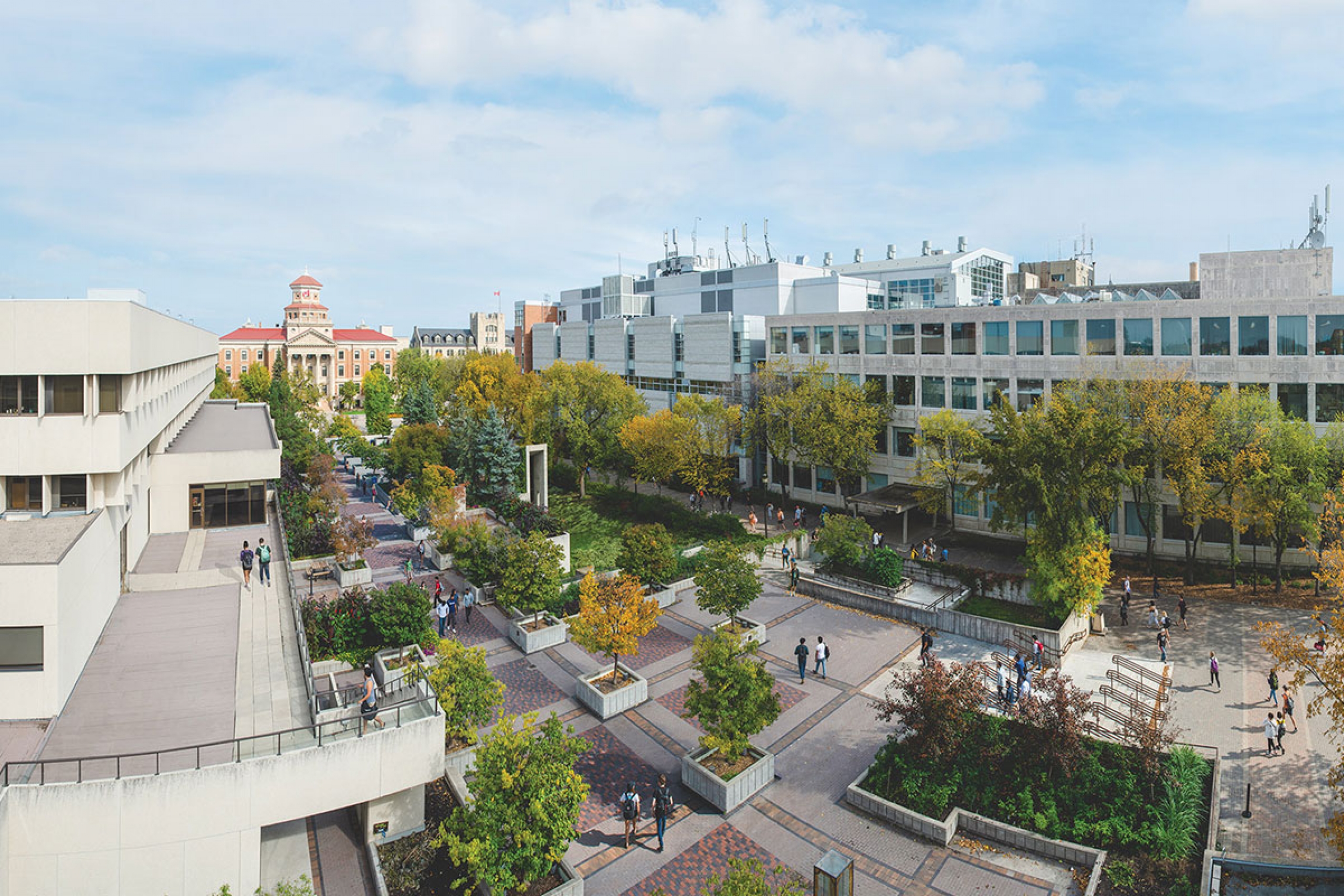 Fort Garry campus from above, showing trees, a walking path, and mid-century buildings.