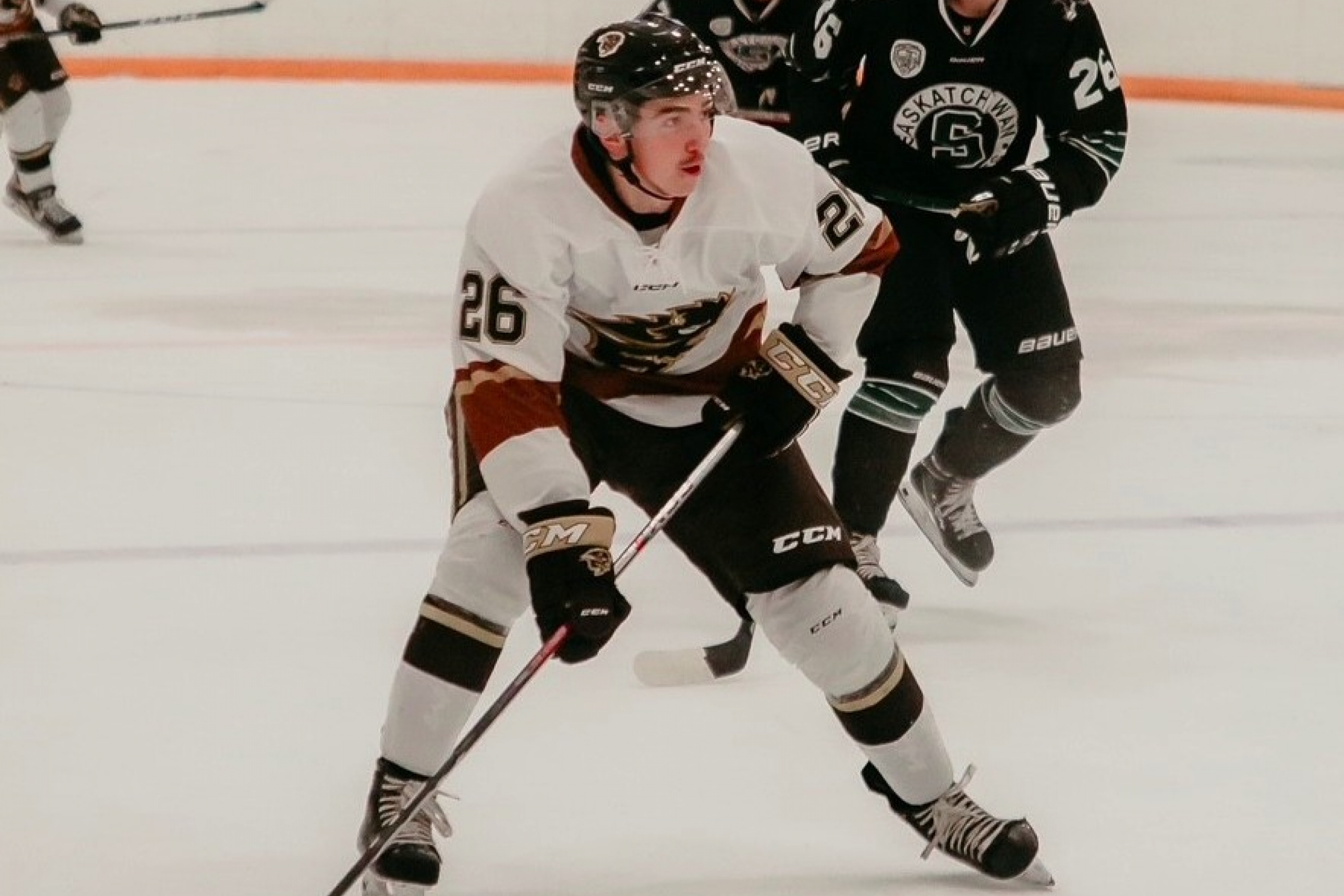 Andrew Boucher plays hockey, skating among other players on an indoor rink.