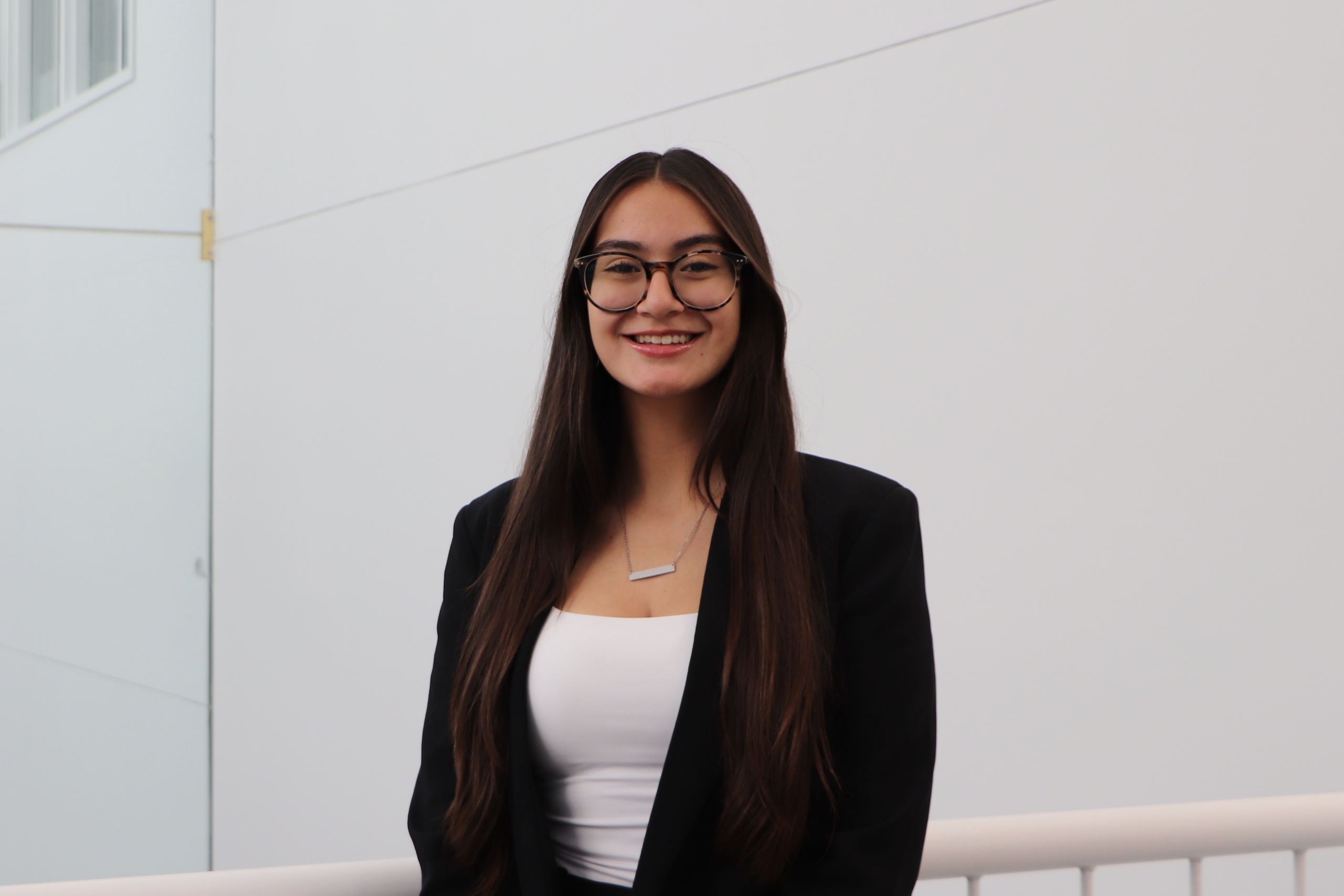 Portrait of Aubrey wearing blazer against white wall.