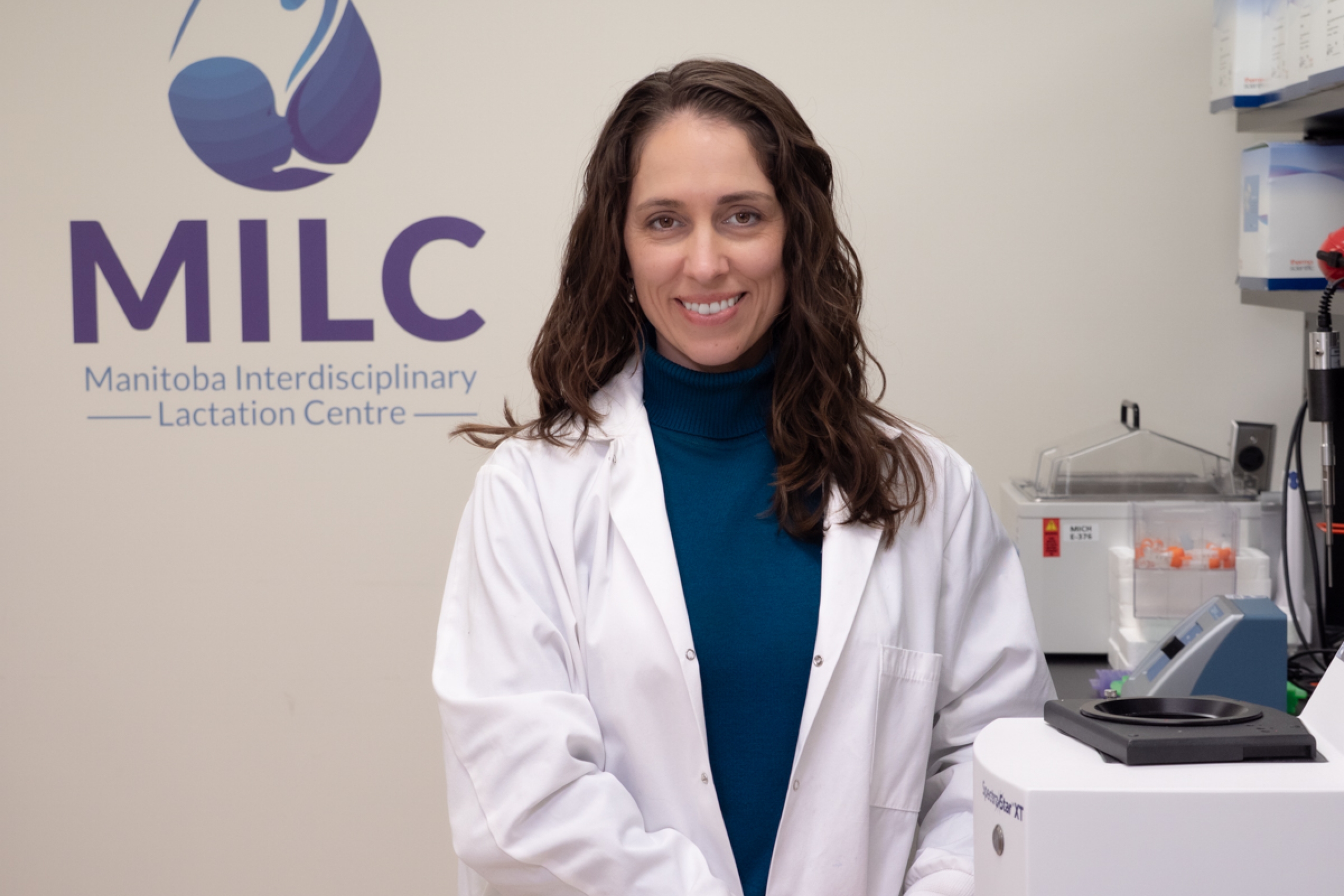 Dr. Meghan Azad in a laboratory, smiling at the camera.
