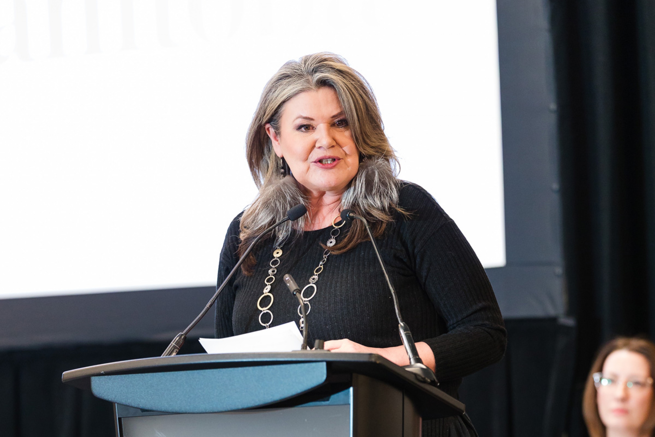 Melanie MacKinnon speaks at a podium.