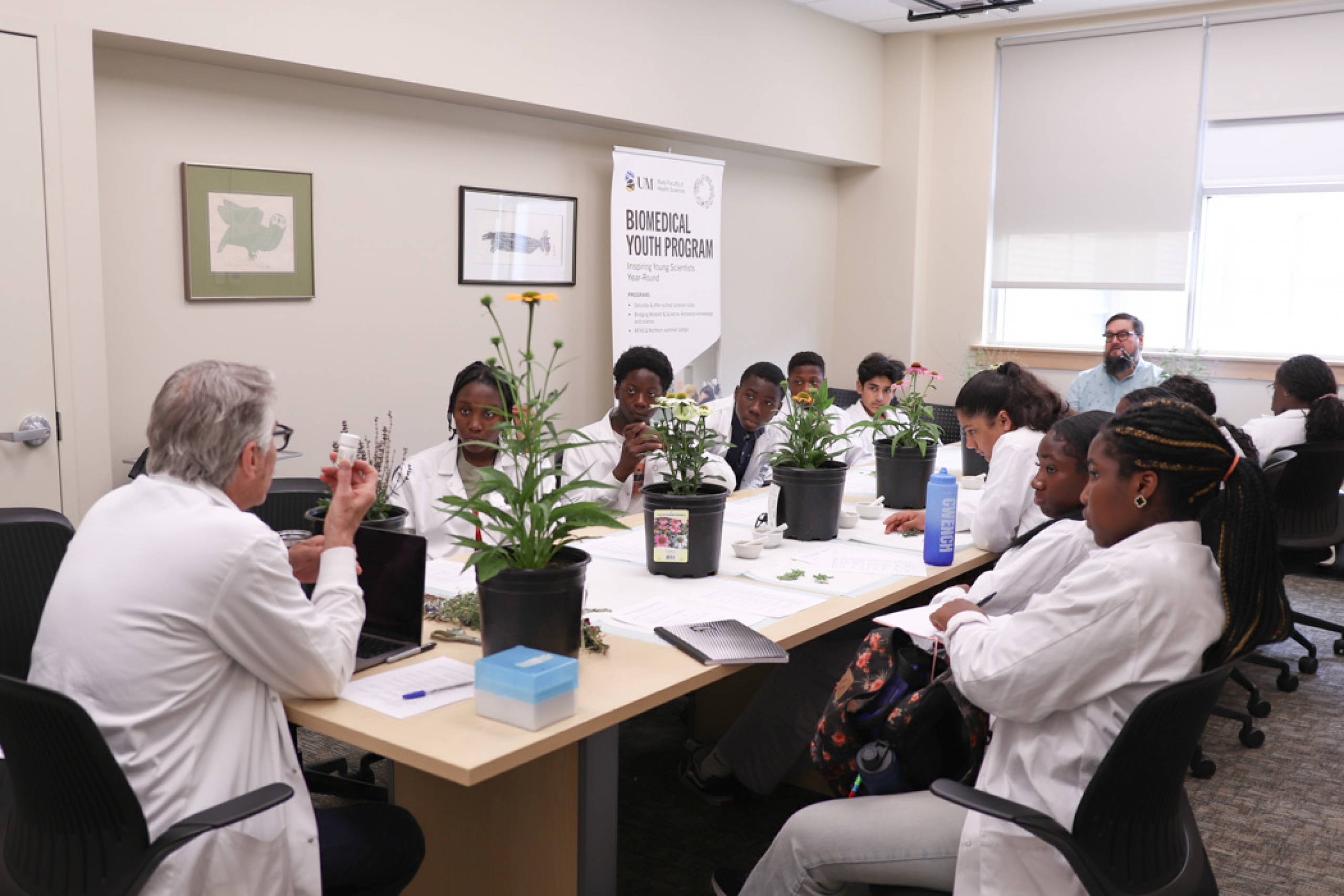 Dr. Gilchrist and Vern Dano lead the Ancestral Knowledge session, seated at opposite ends of a long table as campers listen to their conversation about traditional Indigenous medicines.