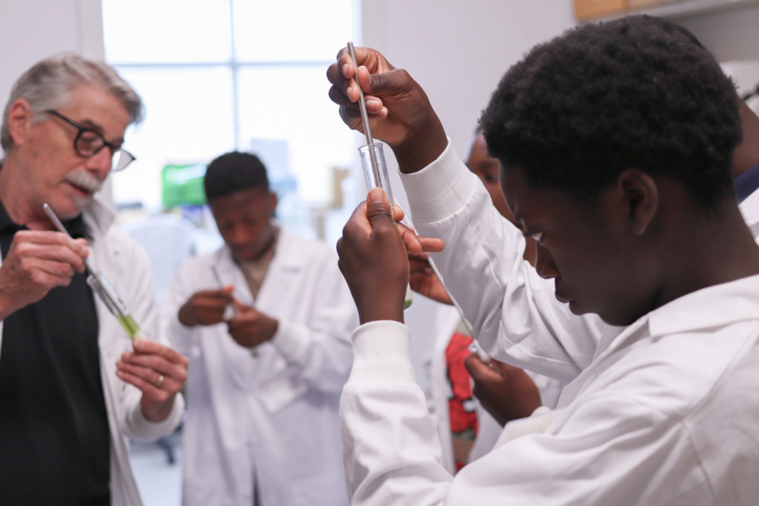 Dr. Gilchrist and campers hold a test tube-like apparatus during a lab activity.
