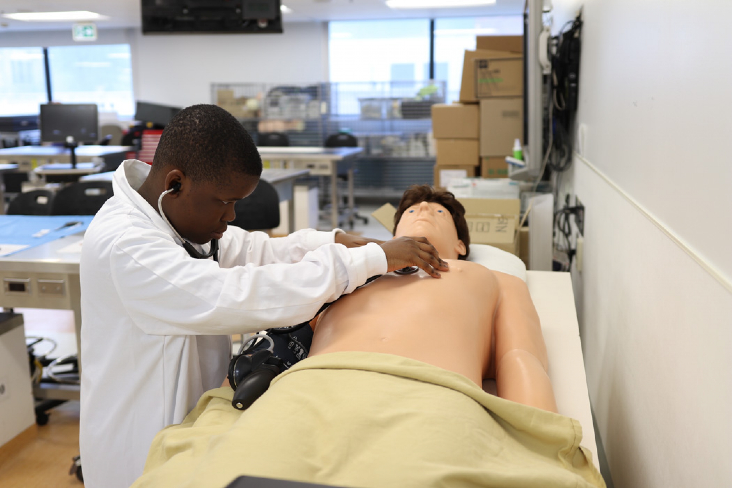 A young camper holds a stethoscope to a manikin, listening to a simulated heartbeat.
