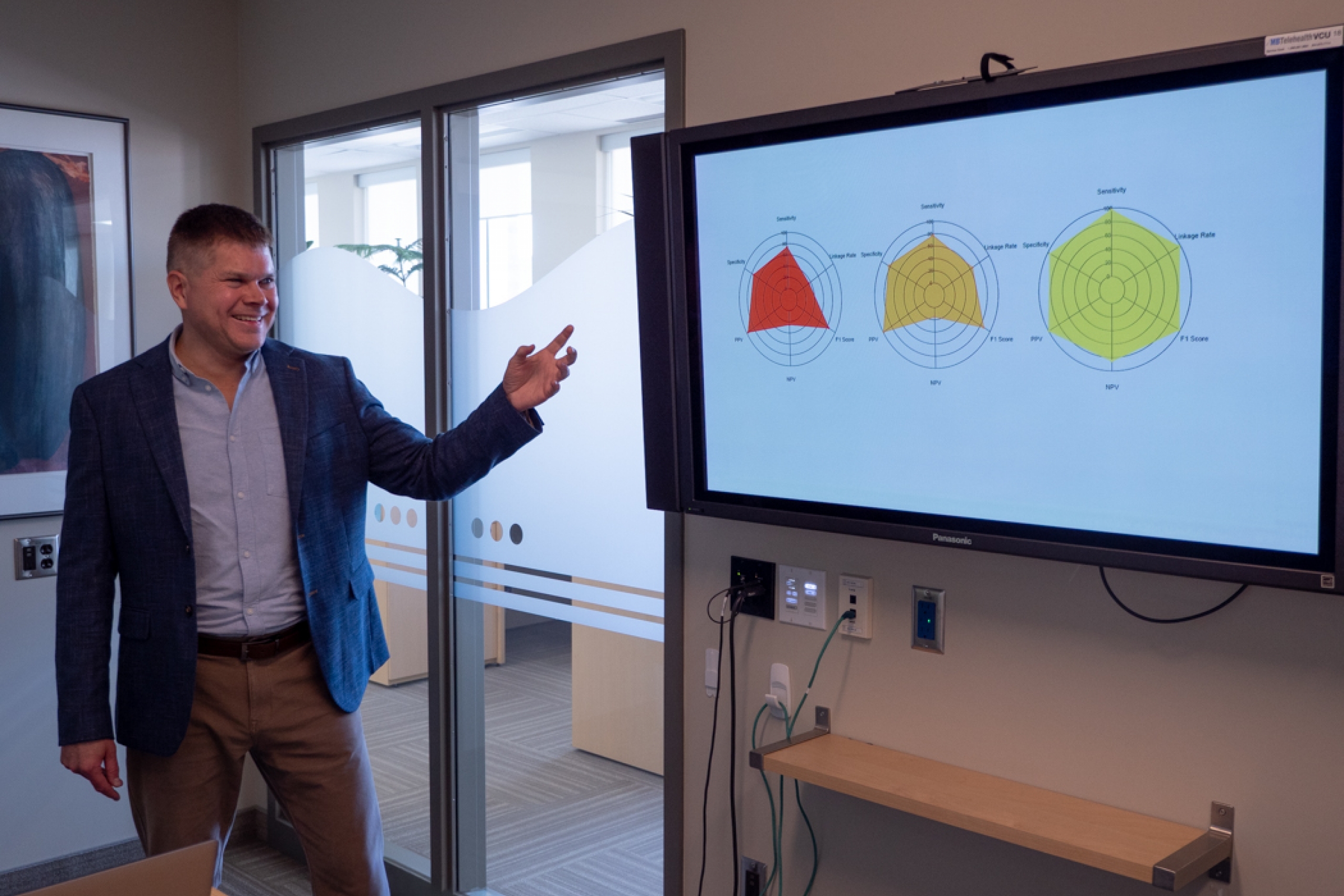 Barret Monchka presents while pointing at a screen displaying a presentation slide.
