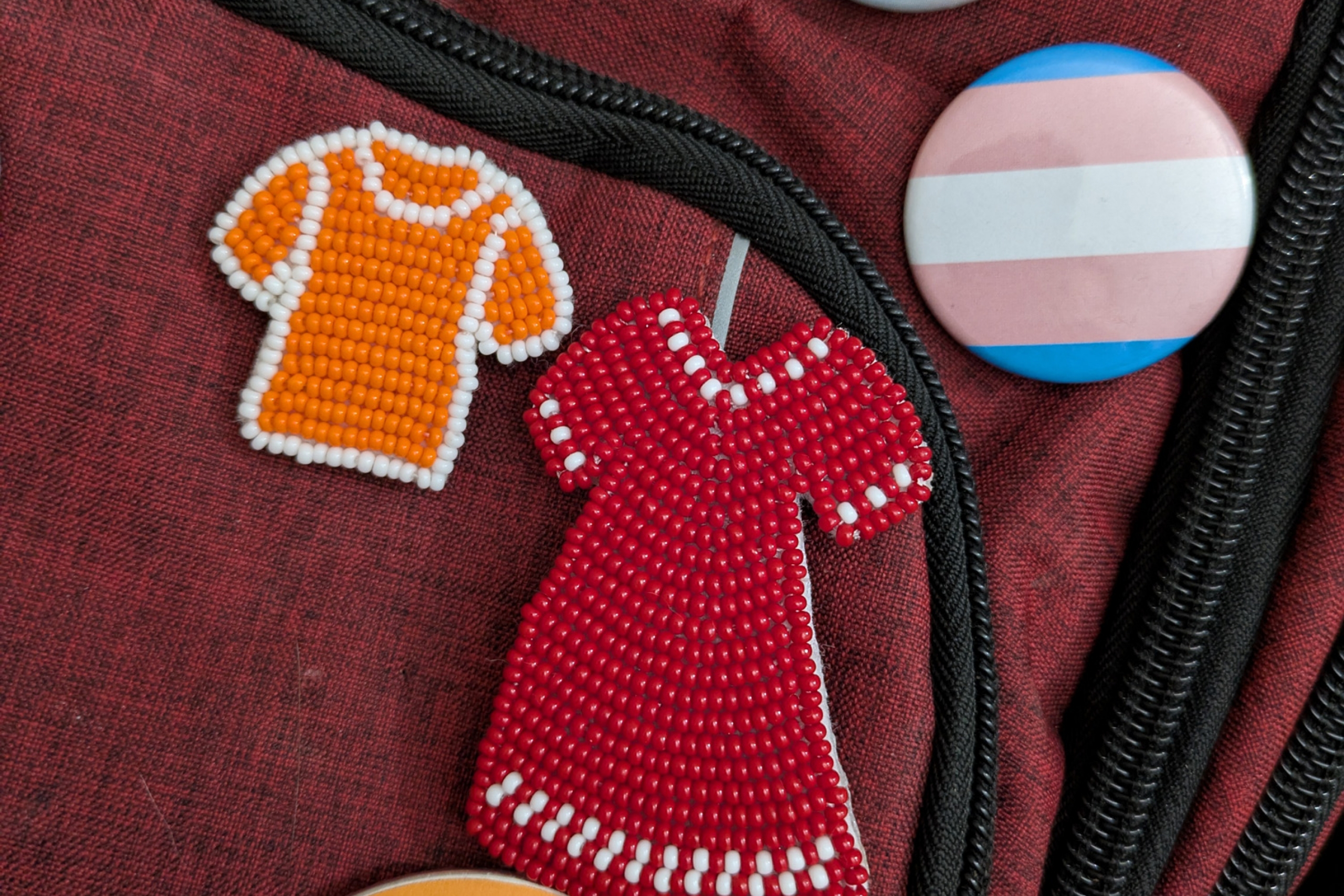 Beaded red dress and orange shirt pins and an assortment of classic button pins.
