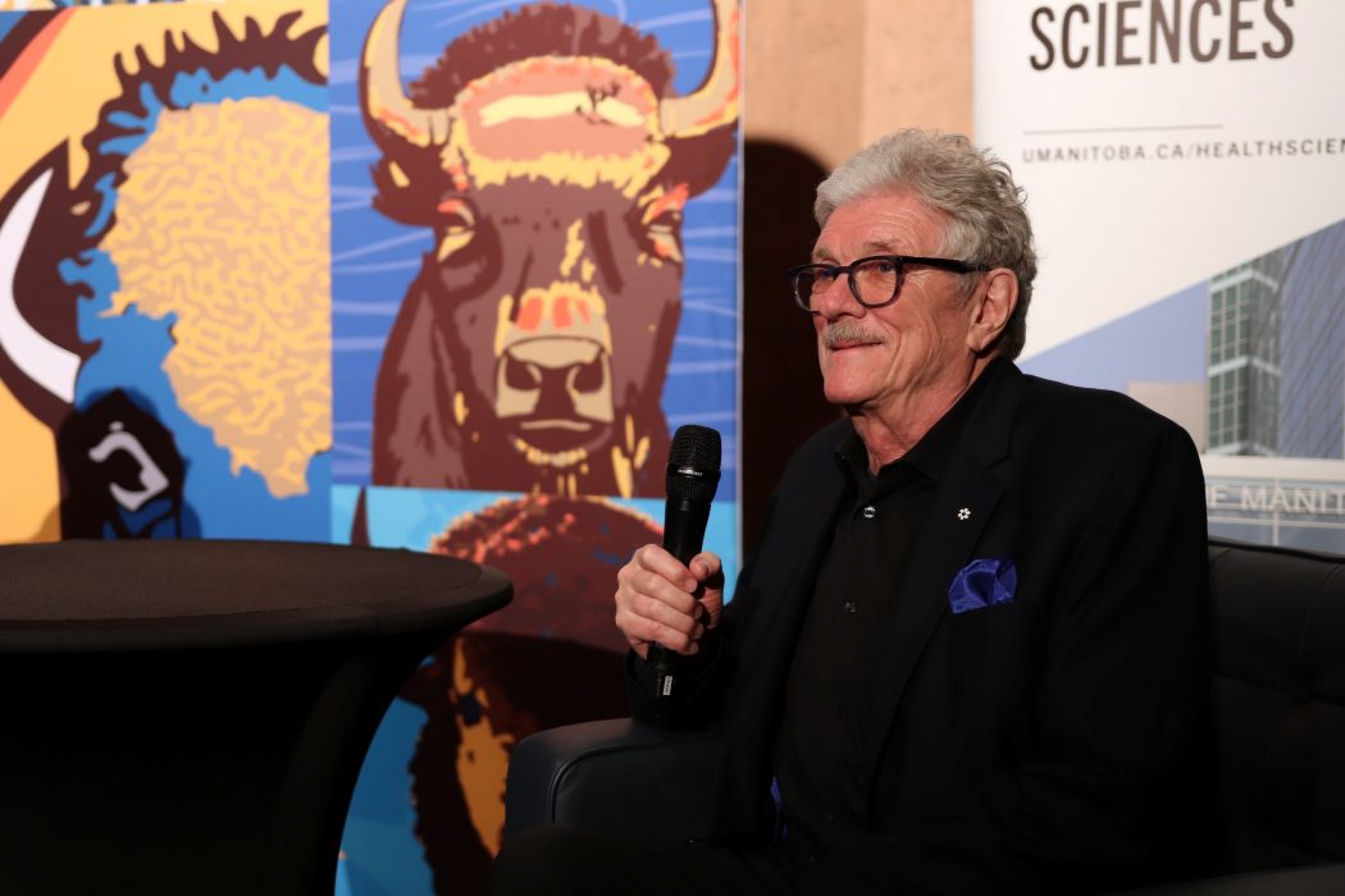 One person is seated and is holding a microphone. 