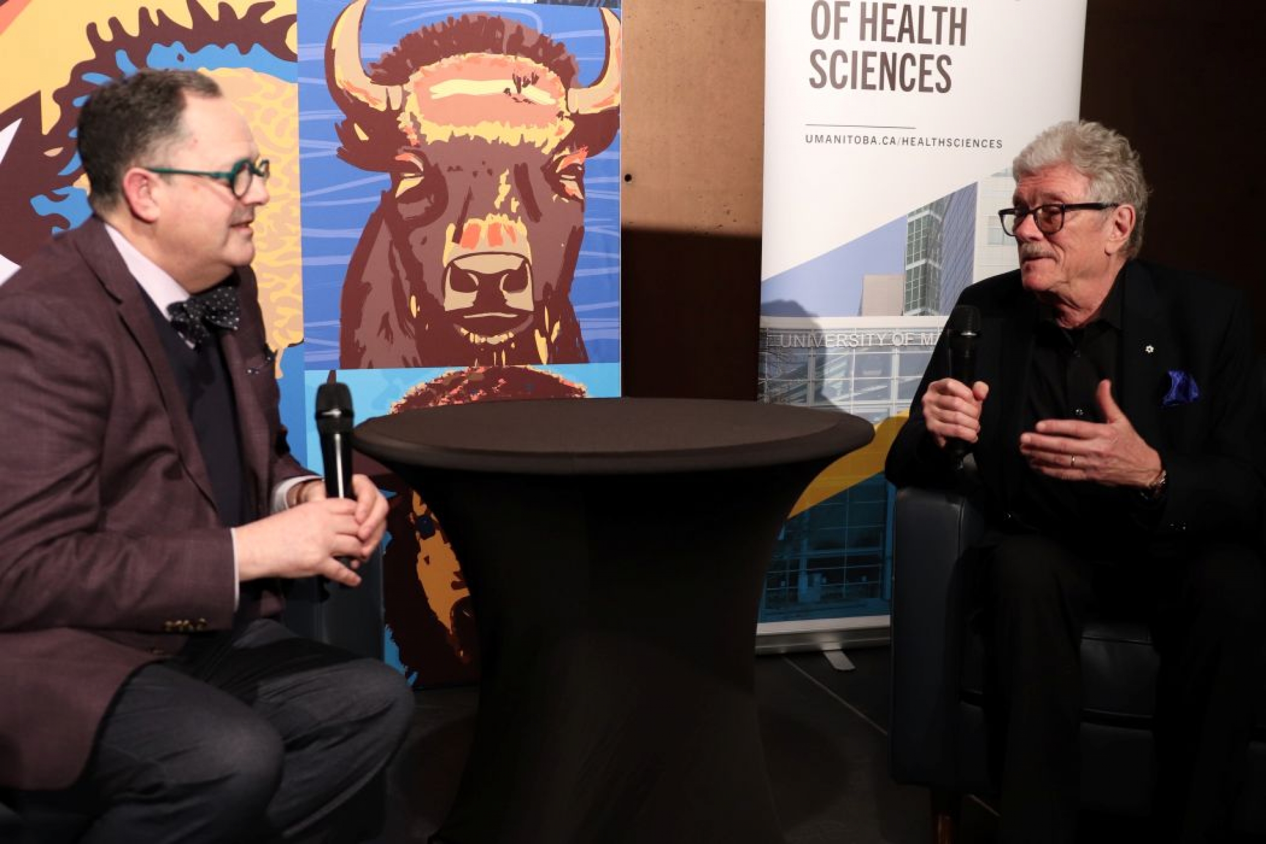 Dr. Philip Berger and Dr. Peter Nickerson are seated and each are holding a microphone.