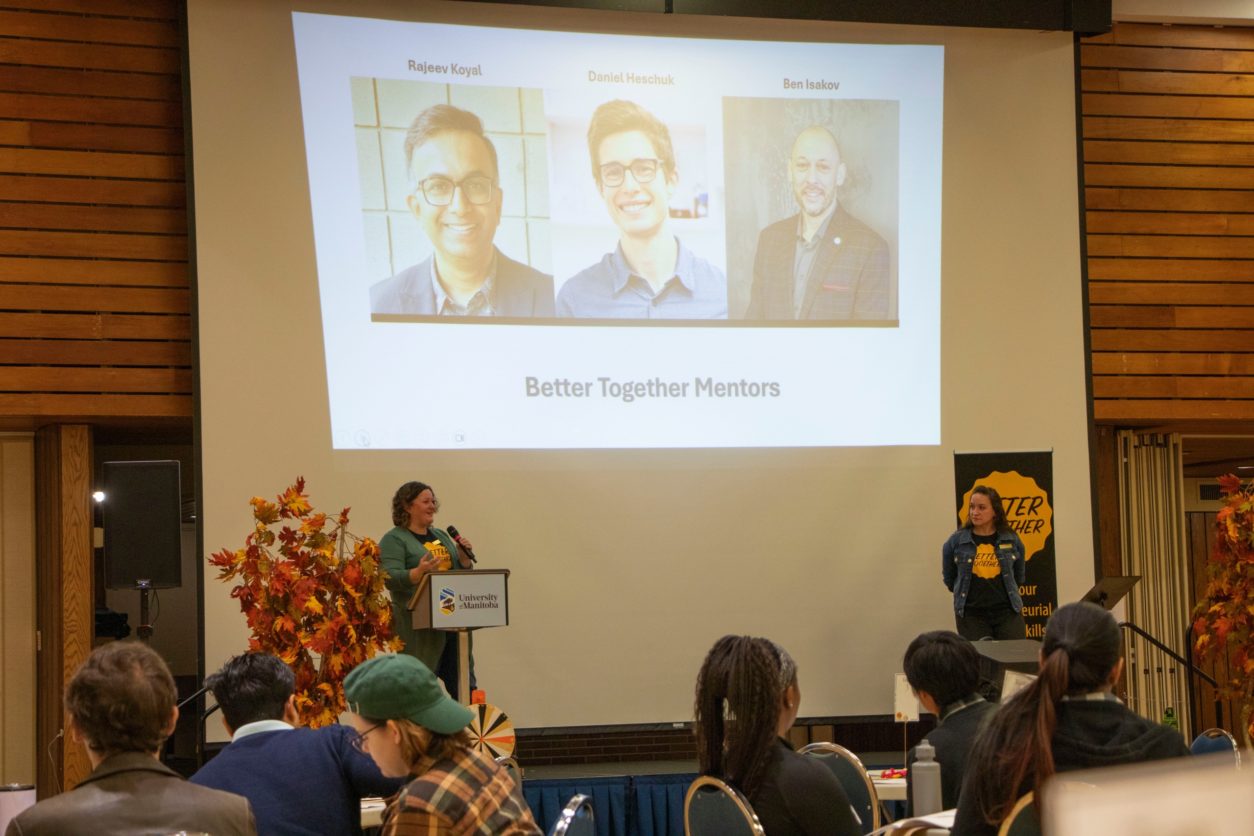 People presenting on a stage with slides projected in the background