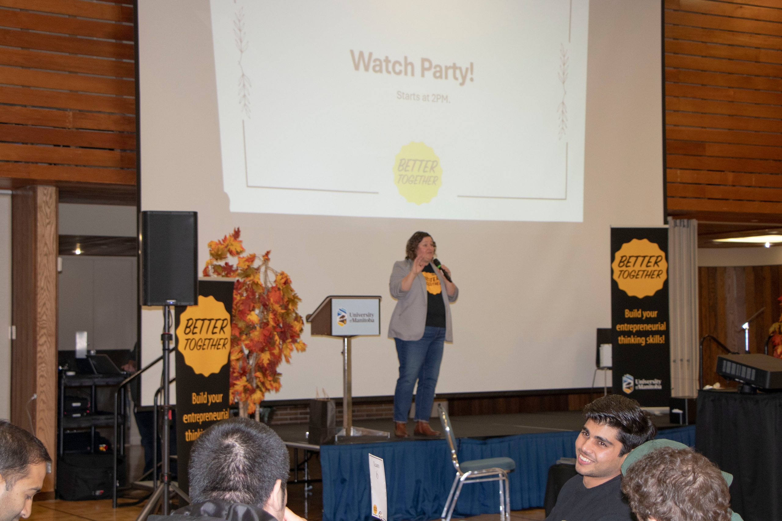 People presenting on a stage with slides projected in the background