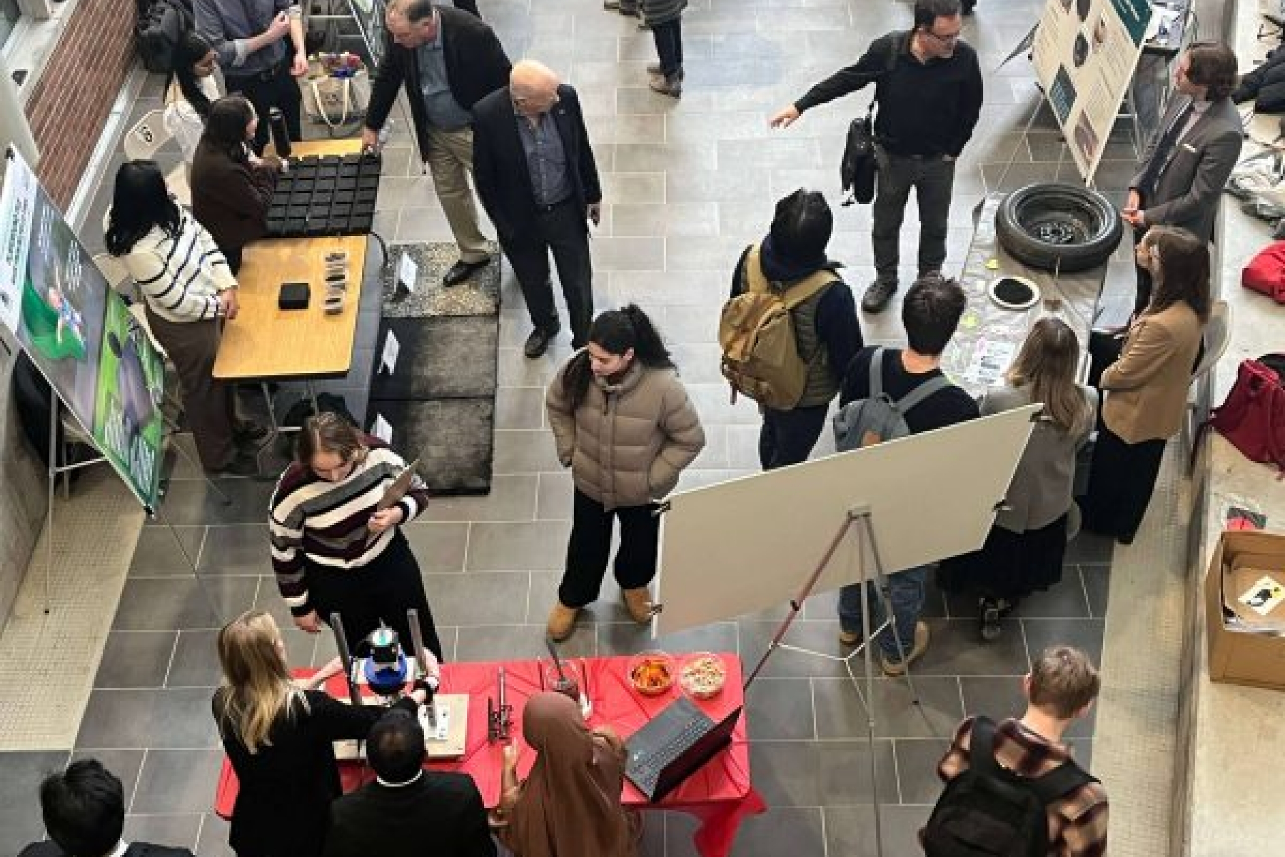 Aerial view of showcase event, crowd of people viewing prototypes and posters