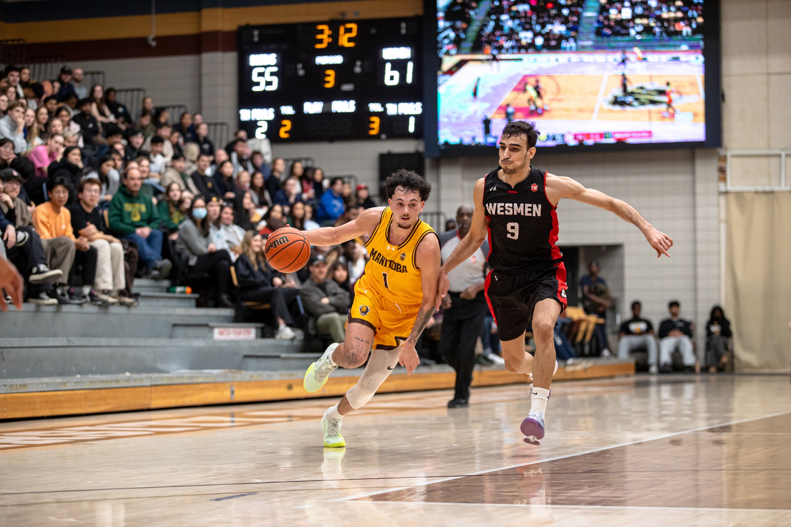 Mason Kraus during a basketball game running past a Winnipeg Wesmen player