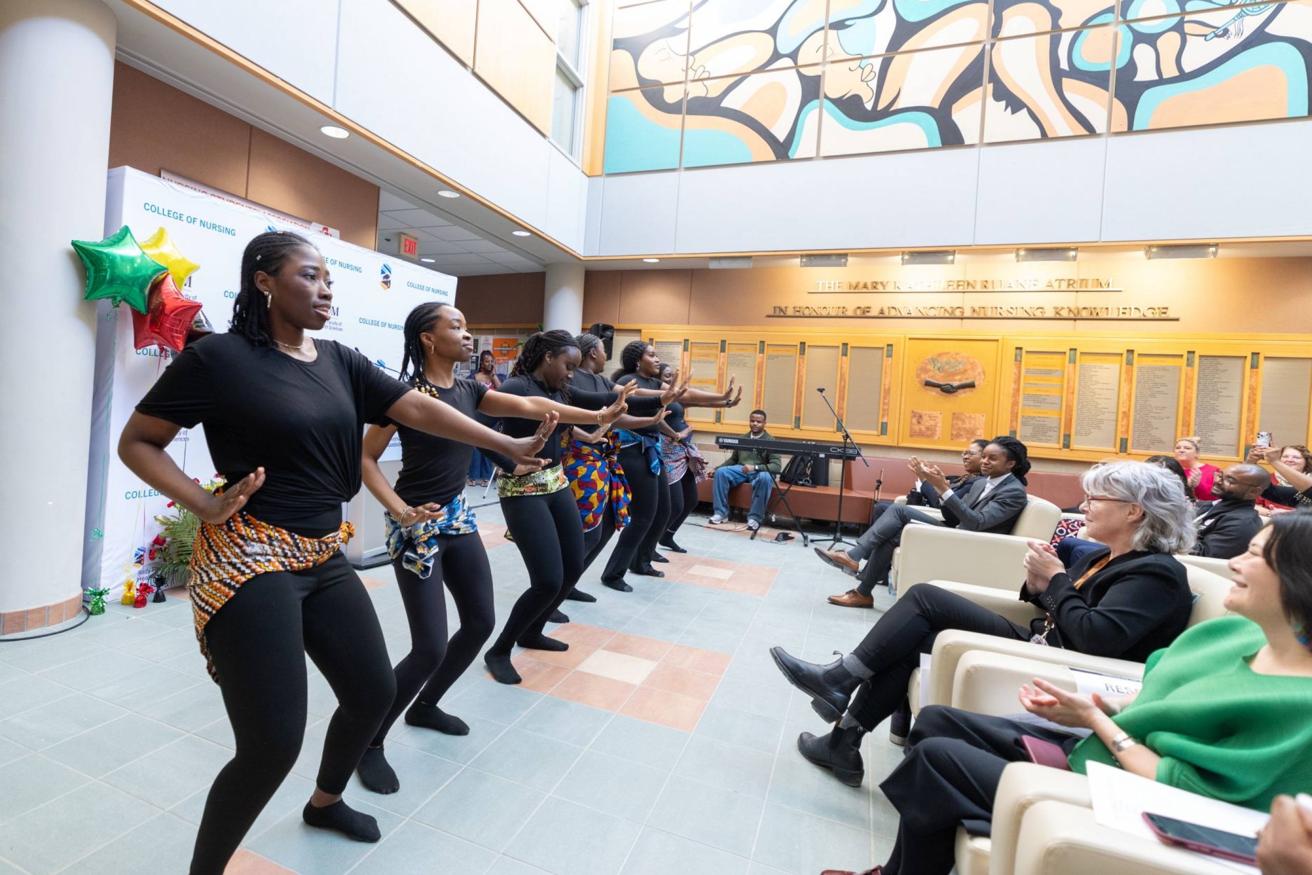A group of Black student perform a cultural dance in front of audience.