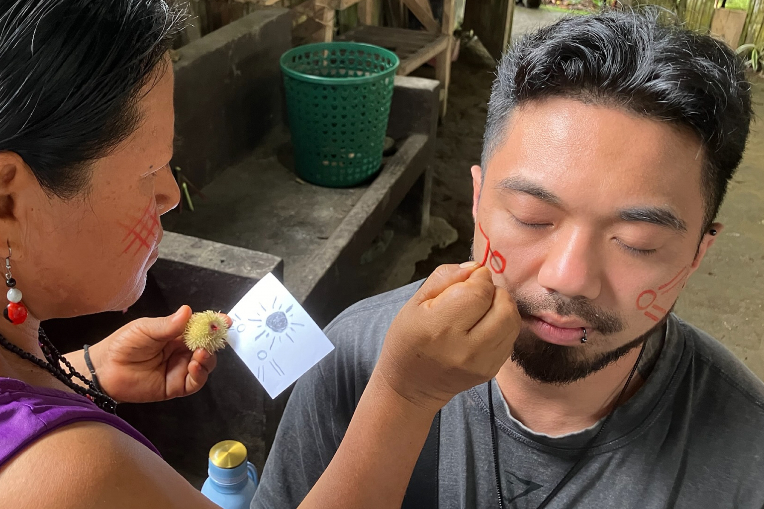 Traditional healer marks a student's face with red fruit.