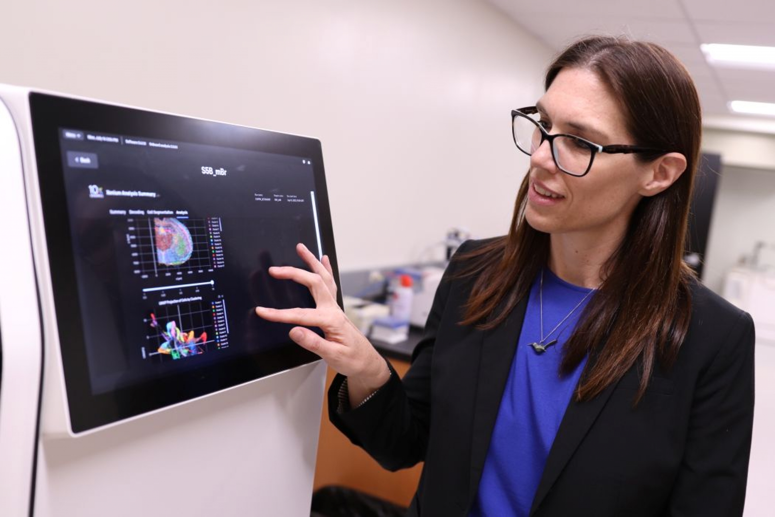 Dr. Britt Drögemöller presses a touchscreen on a large machine used for research.