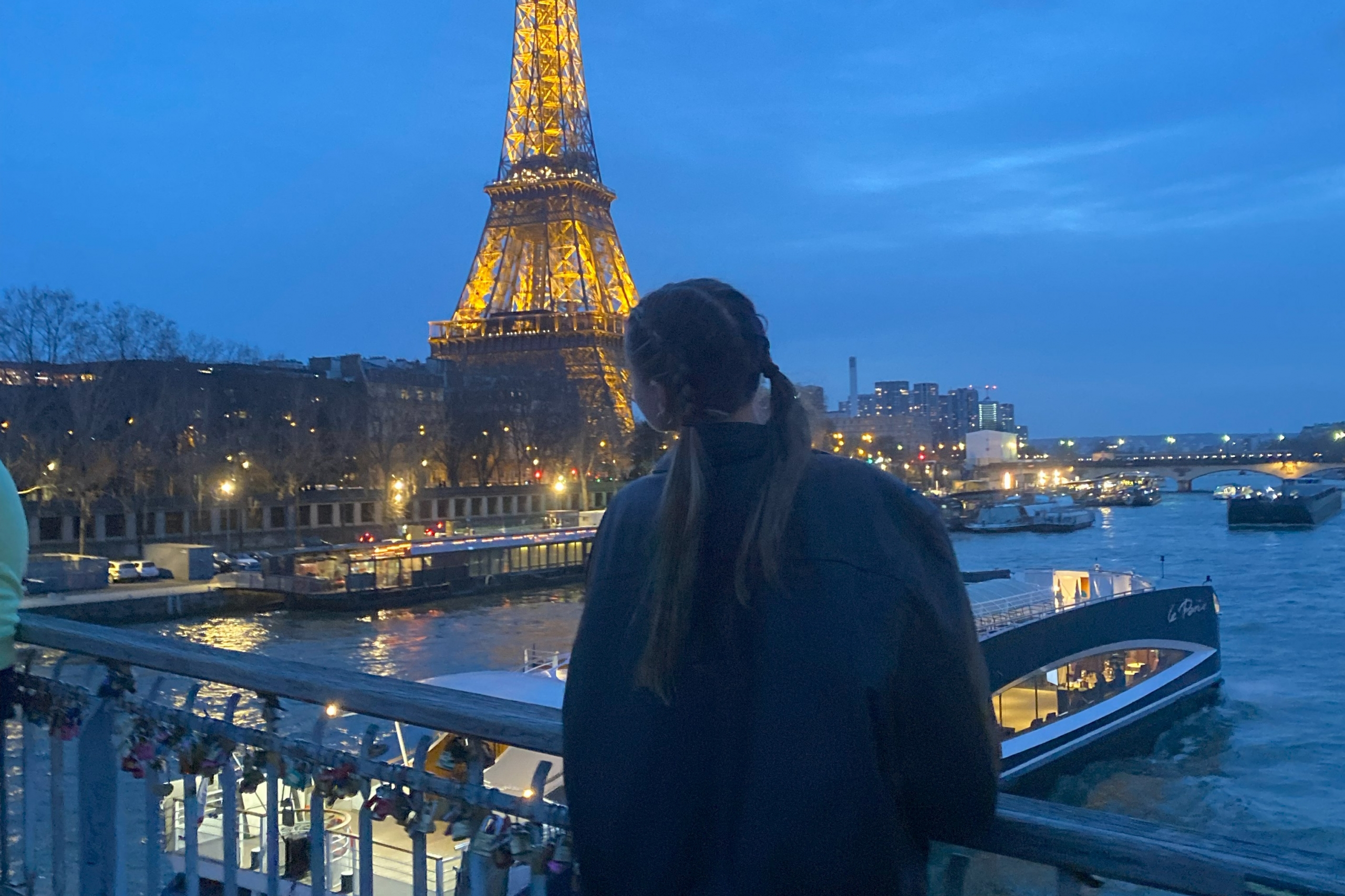 Brooke stands at a railing with the Eiffel Tower in the distance