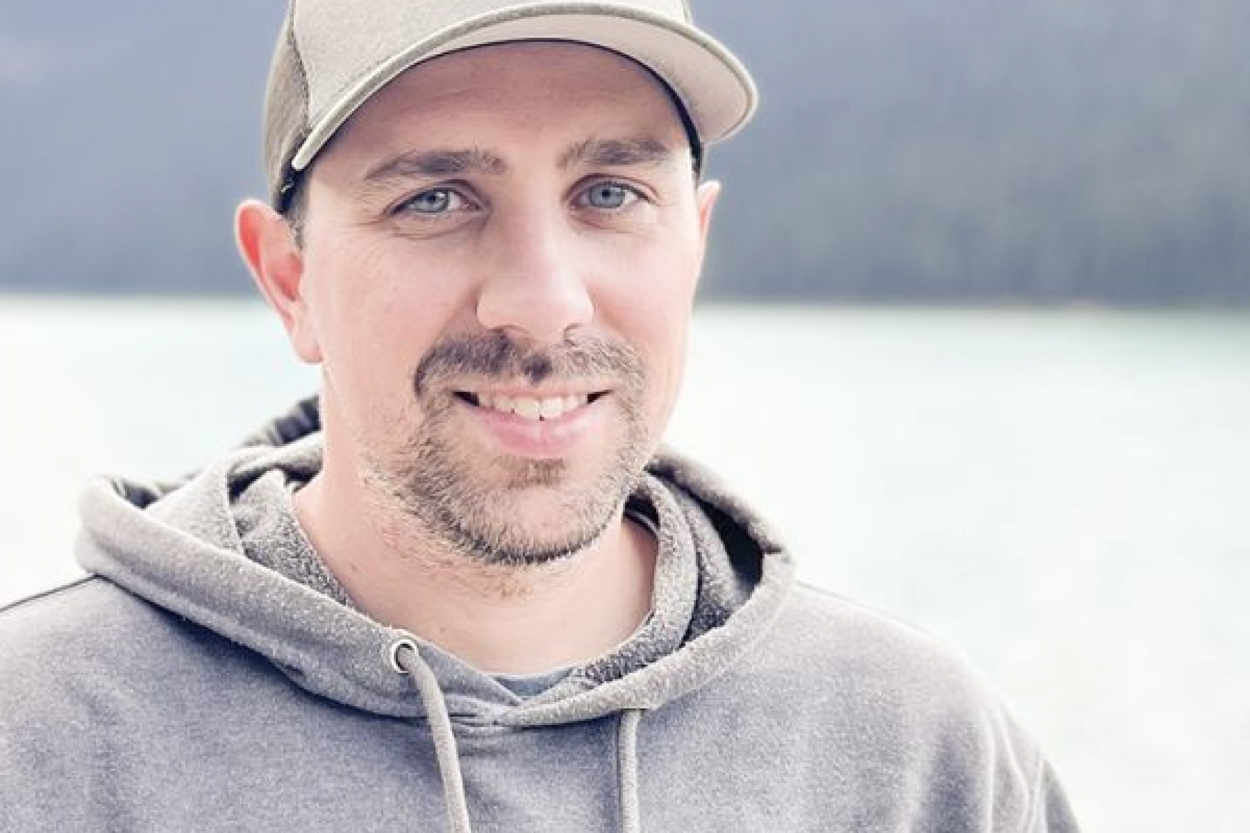A man looking at the camera wearing a gray hat