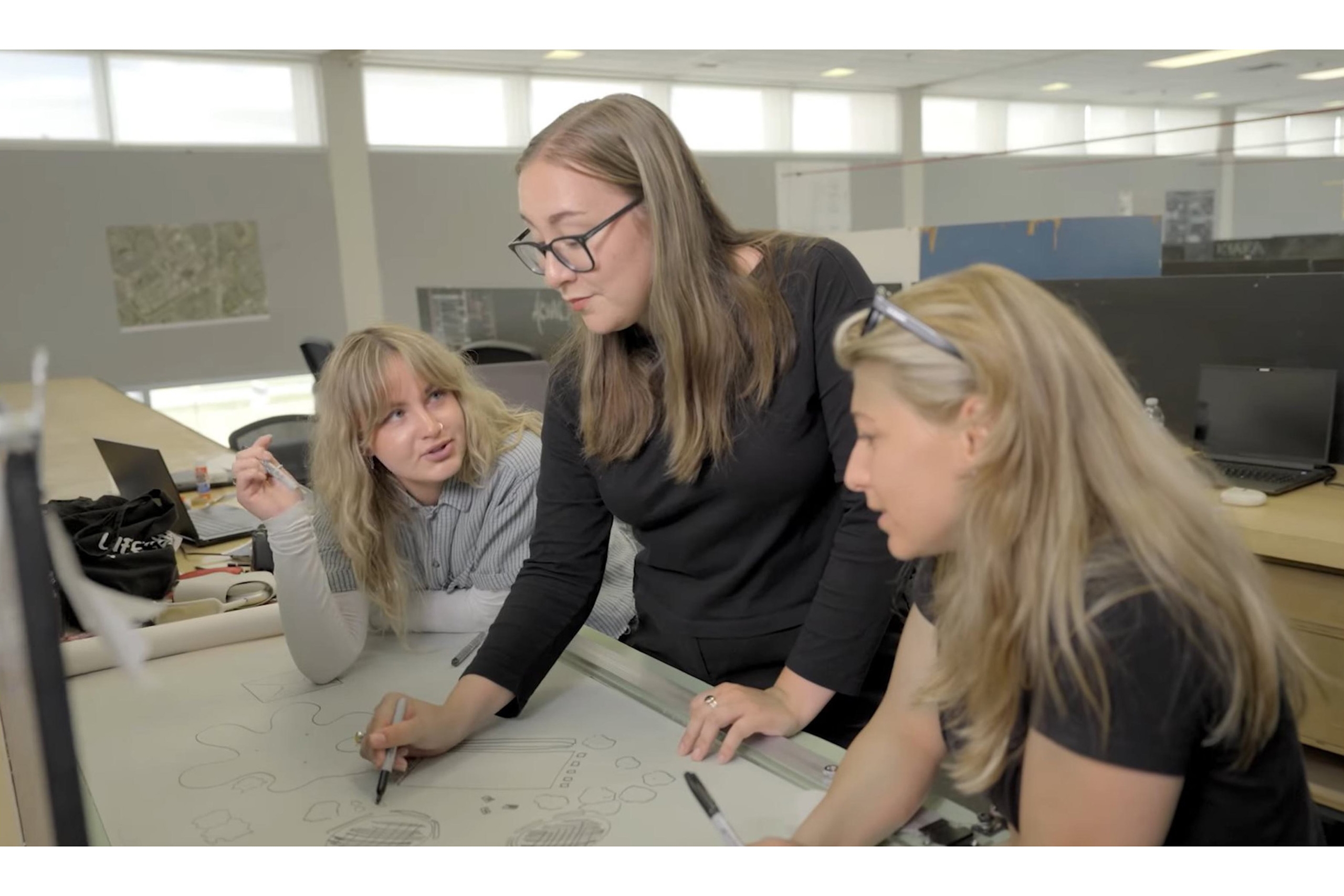 Jory working with fellow environmental design students at a drafting table.