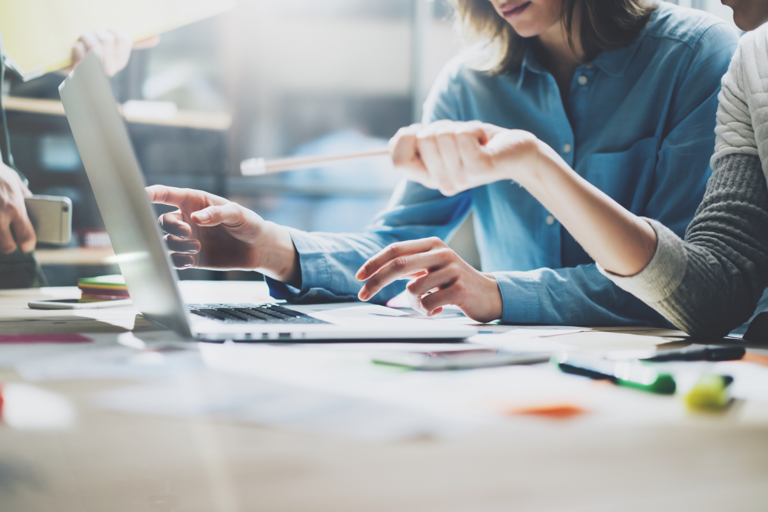 Two people work in front of a laptop