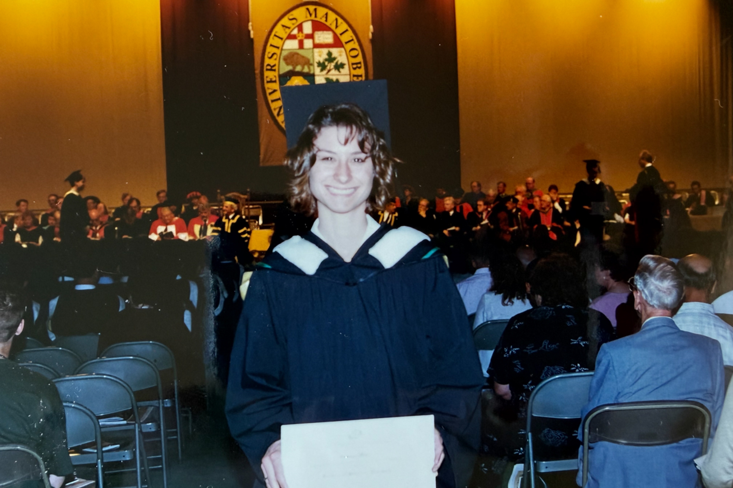 A person in graduation robes at a convocation ceremony.