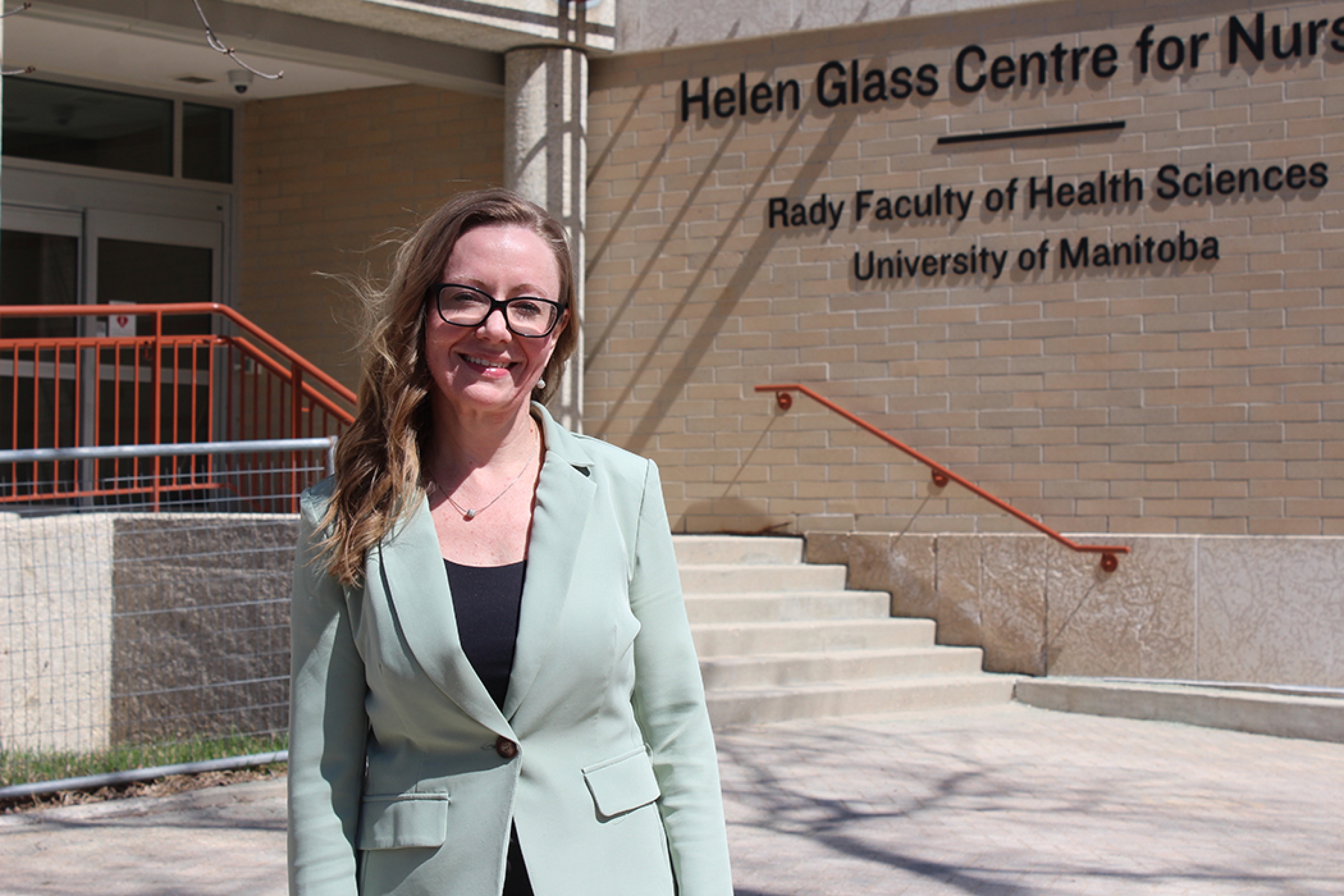 Cheryl Olfert standing outside the Helen Glass Centre for Nursing at Fort Garry campus.